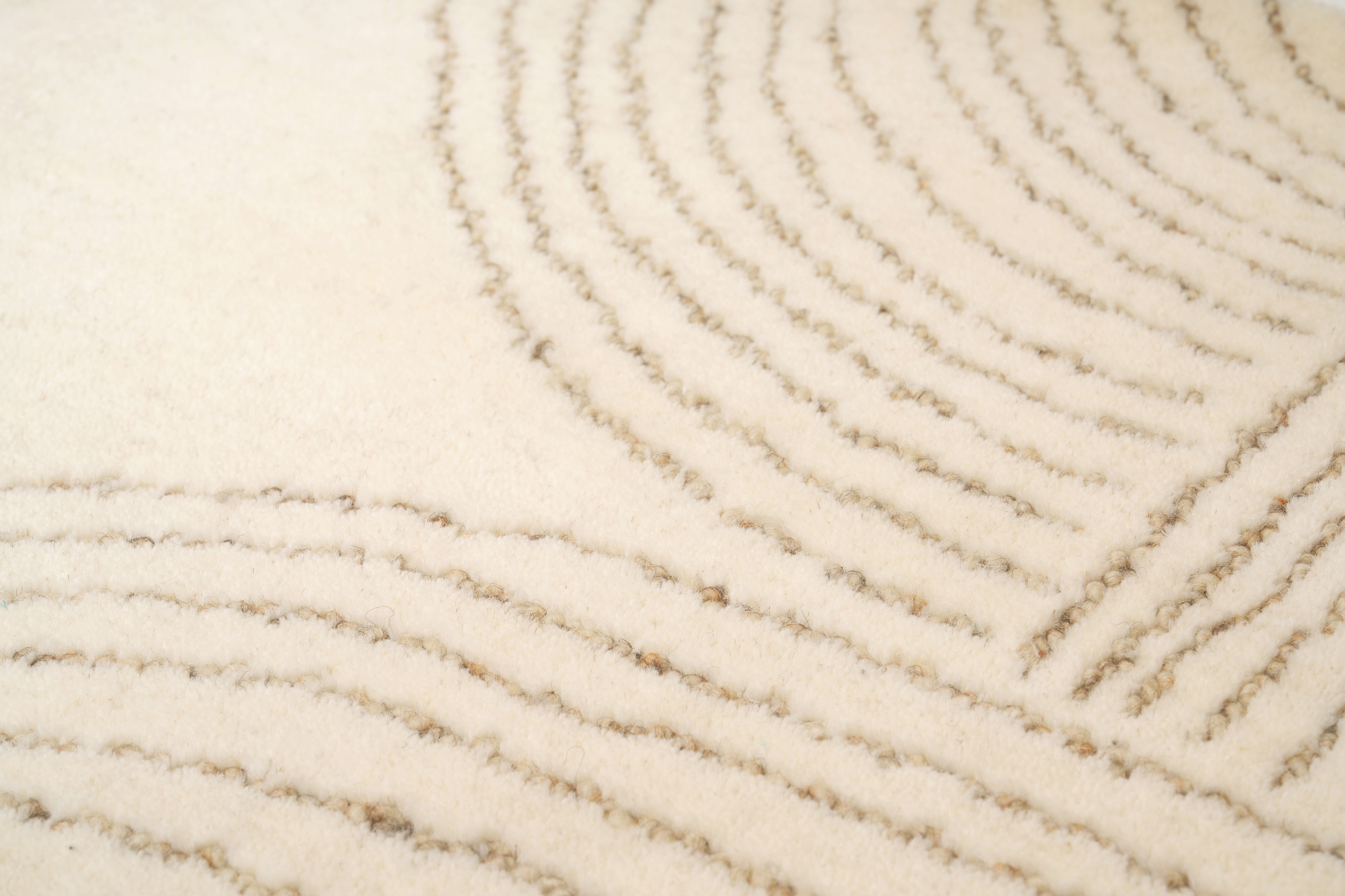 Détail texture d'un tapis beige fait main en laine. Zoom sur les fibres et le tissage rectangulaire.