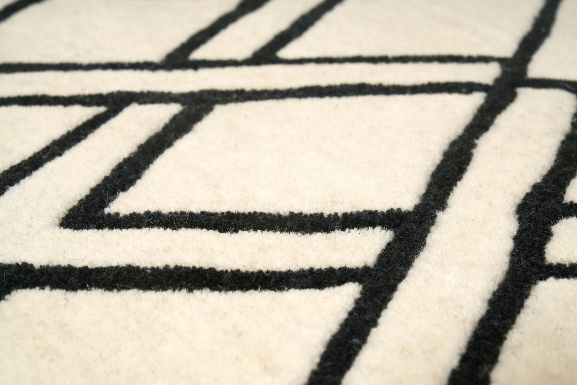 Tapis rectangulaire en laine, tissage dense, motifs géométriques noirs sur fond ivoire, relief et aspect tactile