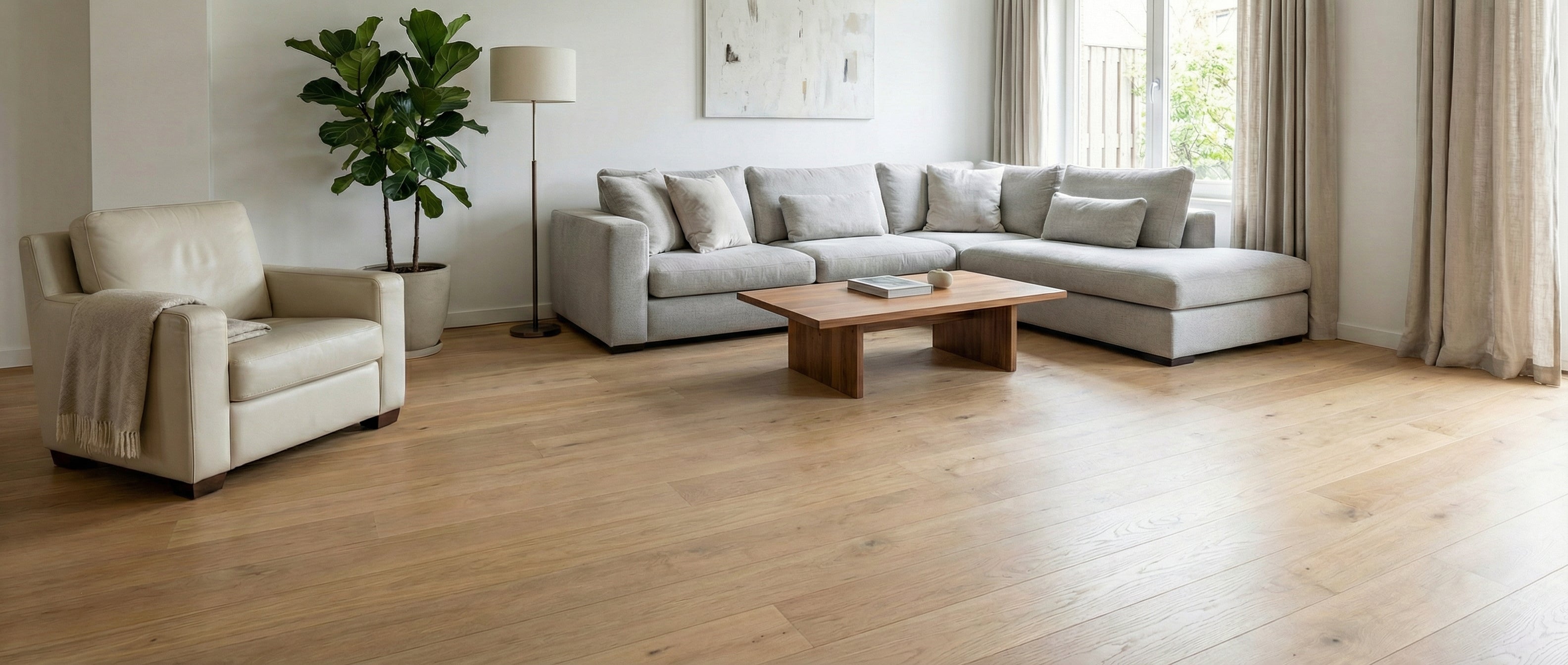 Pièce lumineuse avec canapé gris, fauteuil crème, sol clair. Espace vide pour un tapis rectangulaire, ambiance chaleureuse