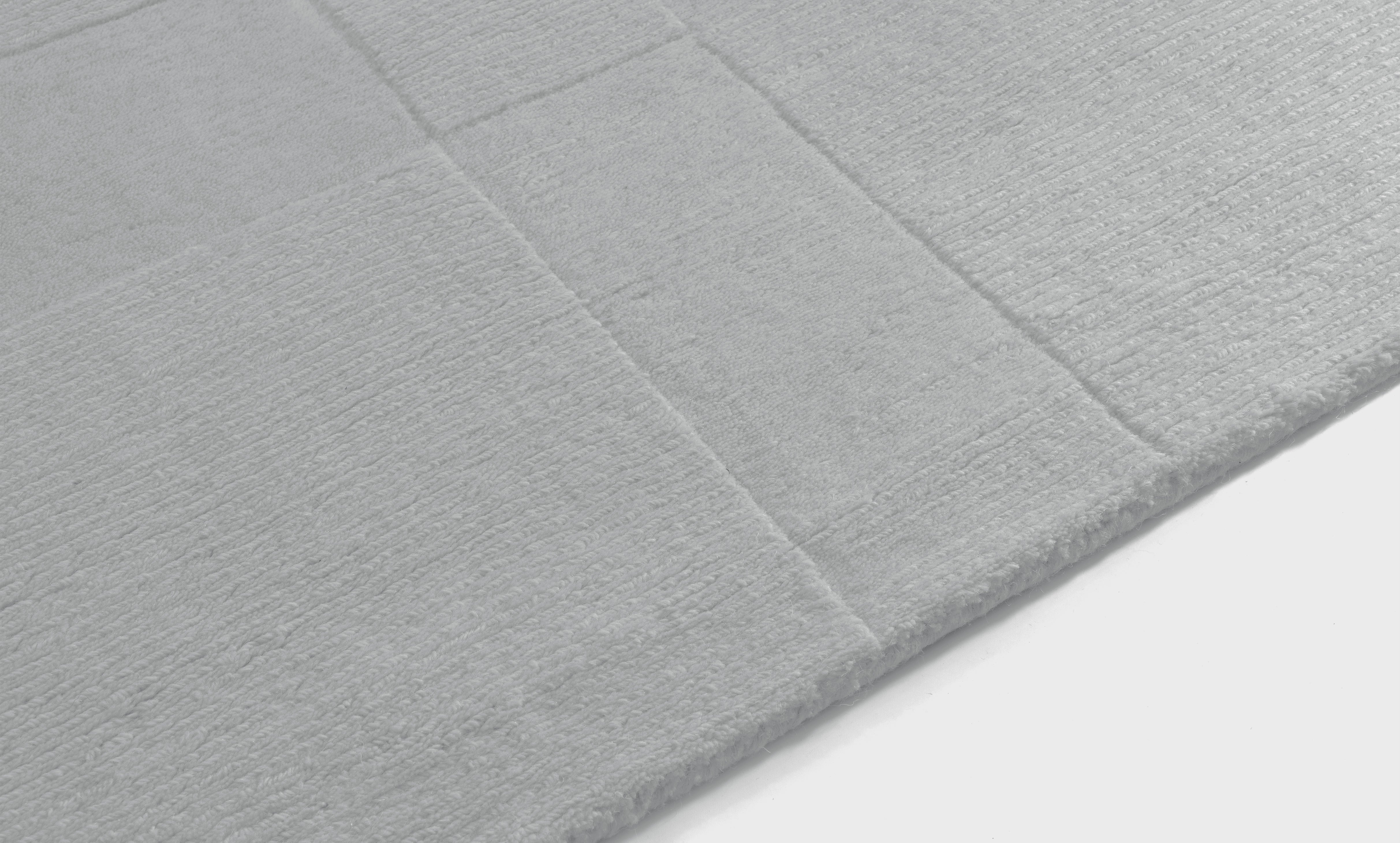 Tapis rectangulaire gris clair, tissage texturé avec relief. Toucher doux et aspect feutré