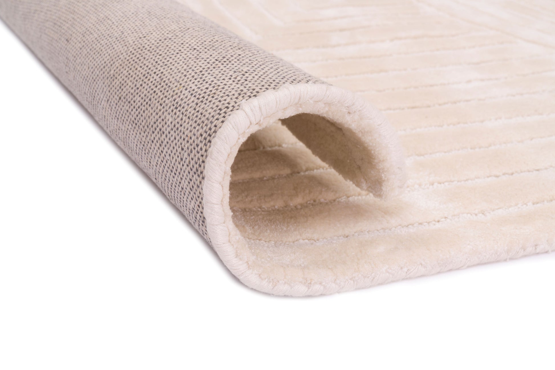 Bordure de tapis crème, finition cousue de qualité. Le dessous est gris clair. Tapis rectangulaire, ambiance chaleureuse