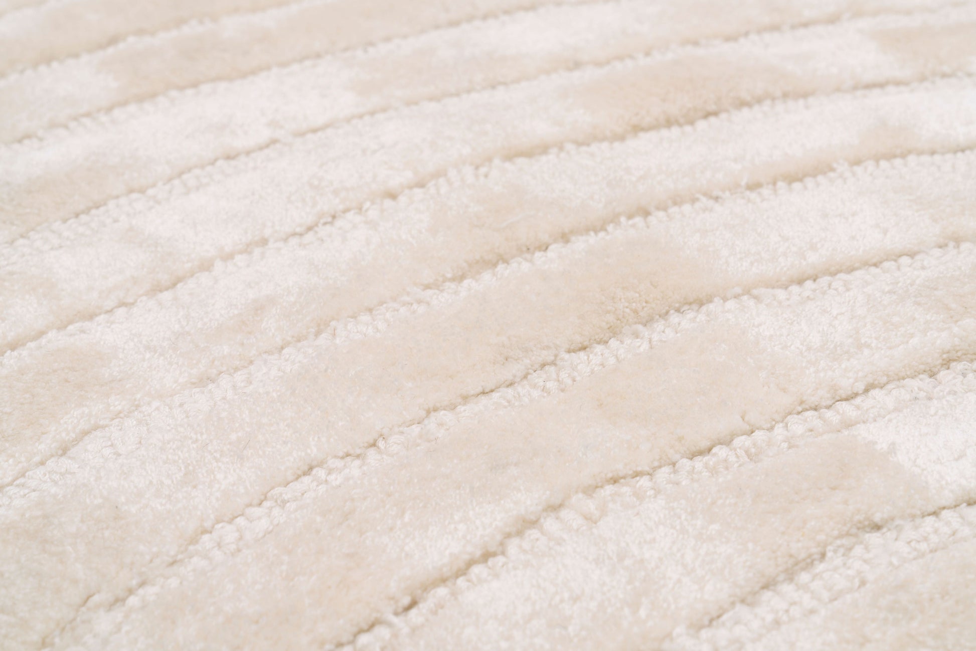 Tapis beige, tissage côtelé en relief. Aspect tactile doux et moelleux. Ambiance chaleureuse