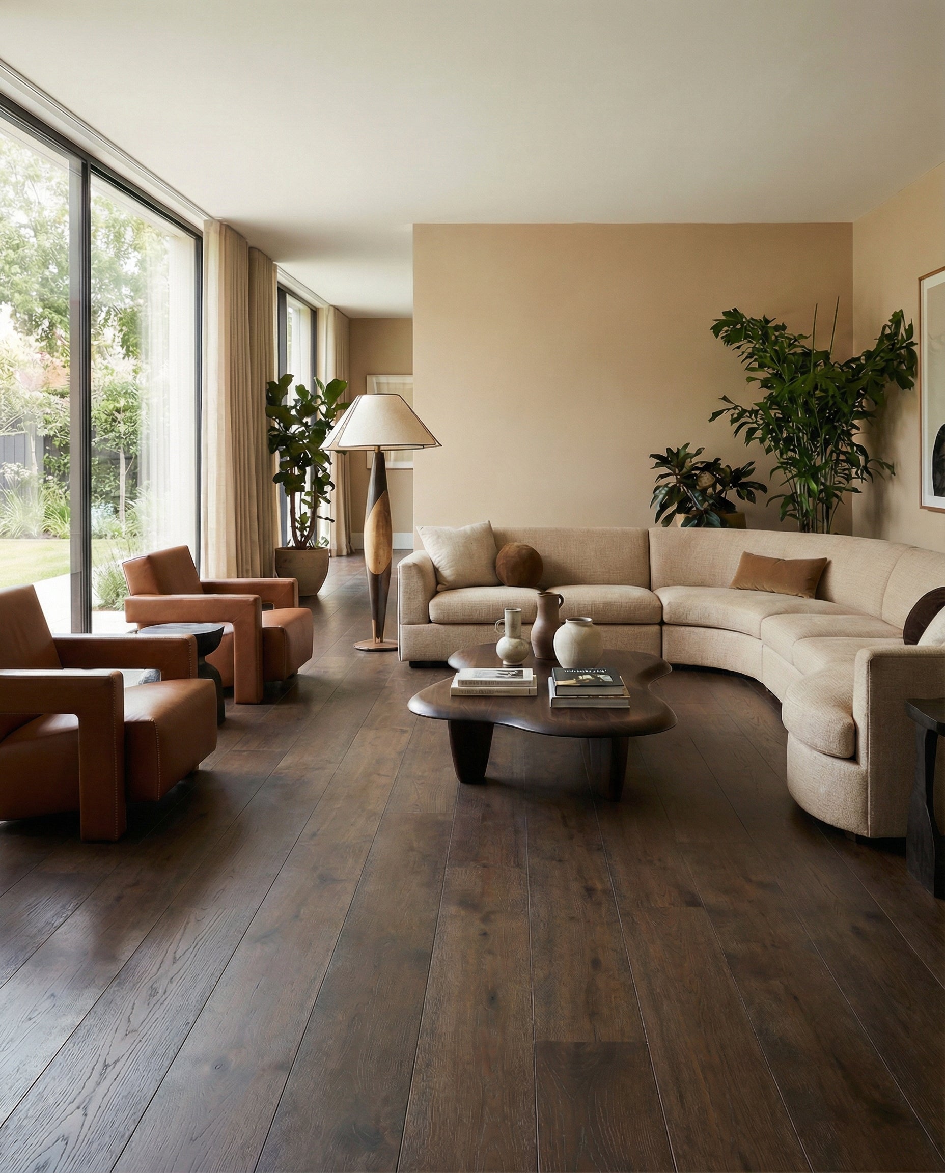 Pièce avec plancher bois foncé, canapé beige en forme de L, fauteuils cuir marron, table basse ovale, ambiance chaleureuse