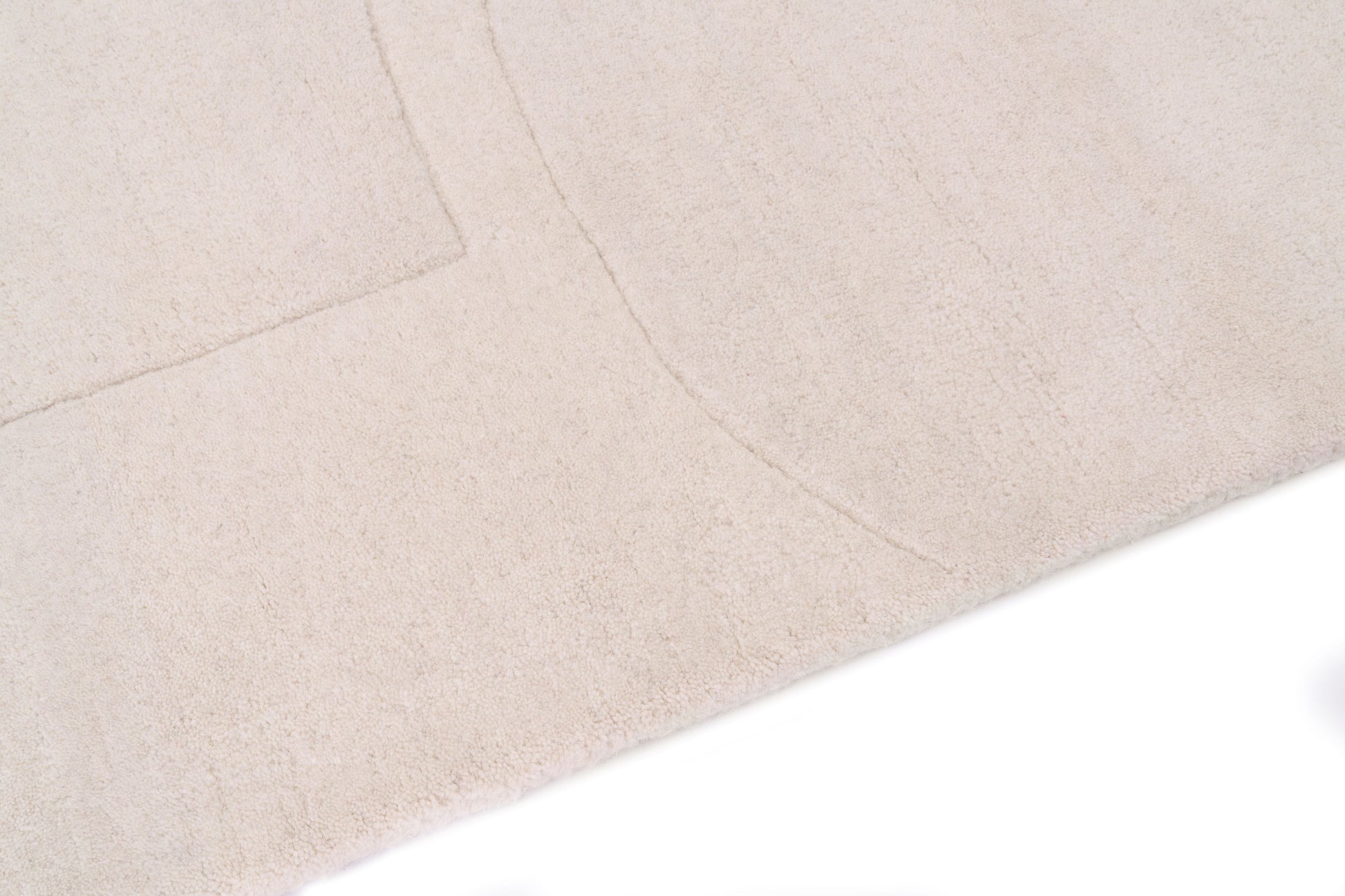 Tapis rectangulaire beige clair, tissage texturé avec relief. Aspect tactile doux et moelleux