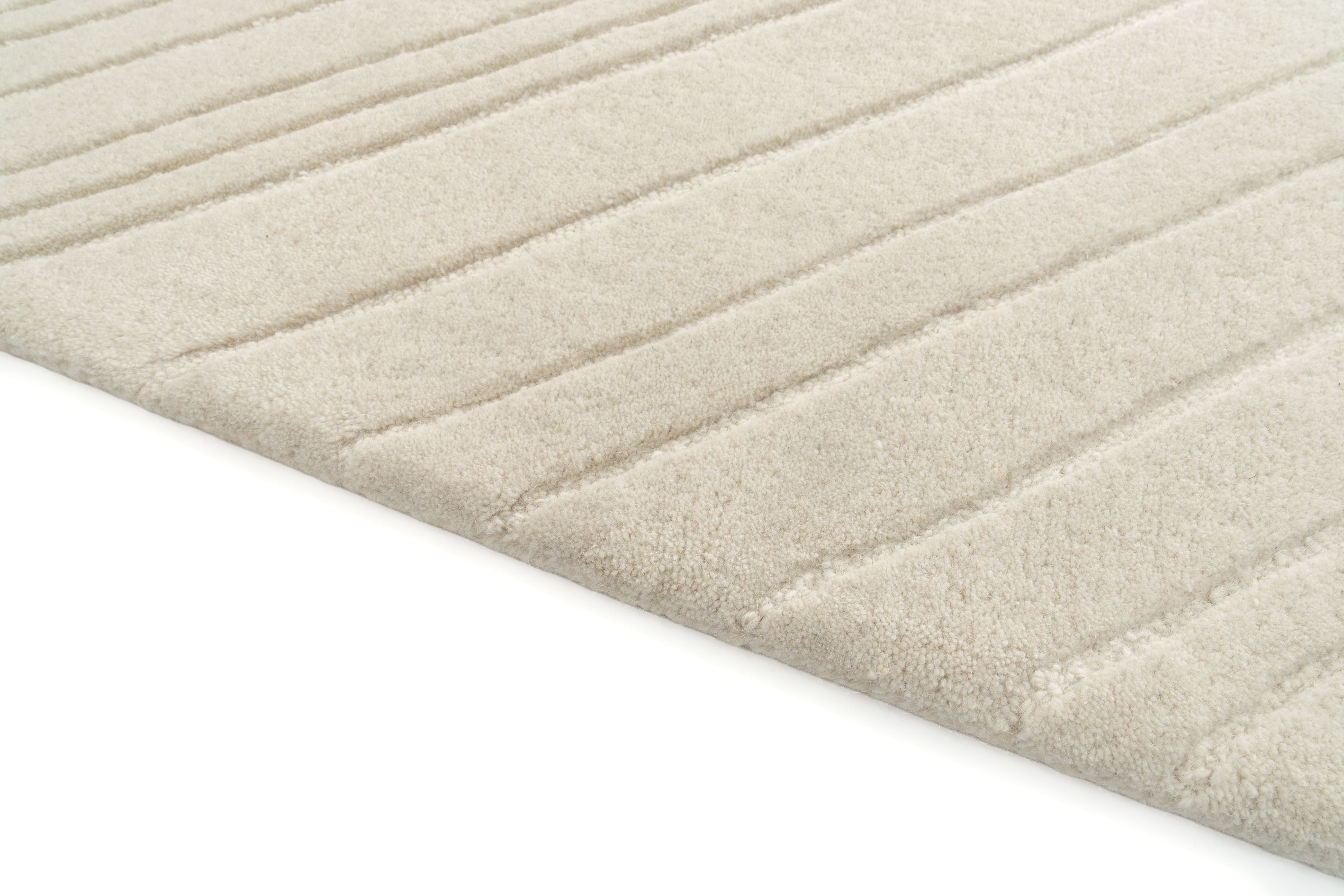 Tapis rectangulaire beige clair avec finition côtelée. Texture douce, ambiance chaleureuse