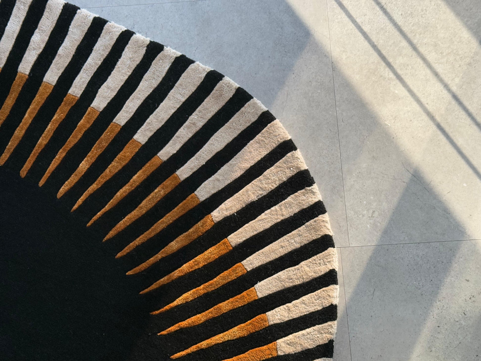 Tapis rond avec finition touffetée. Noir, beige et orange. Tapis de qualité. Pièce décorative