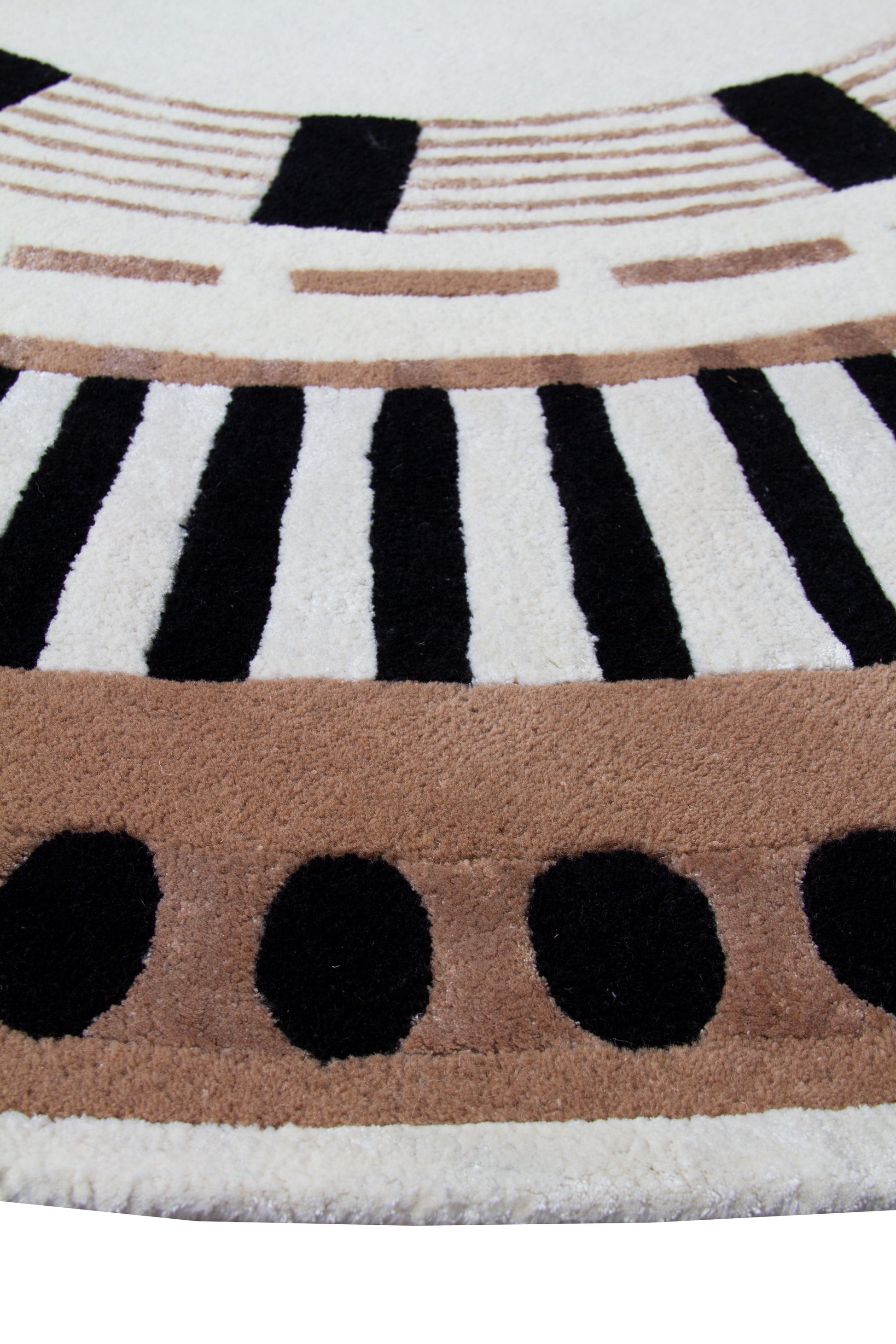 Tapis ovale avec tissage touffeté. Relief doux, aspect tactile. Motifs noirs, bruns et ivoire