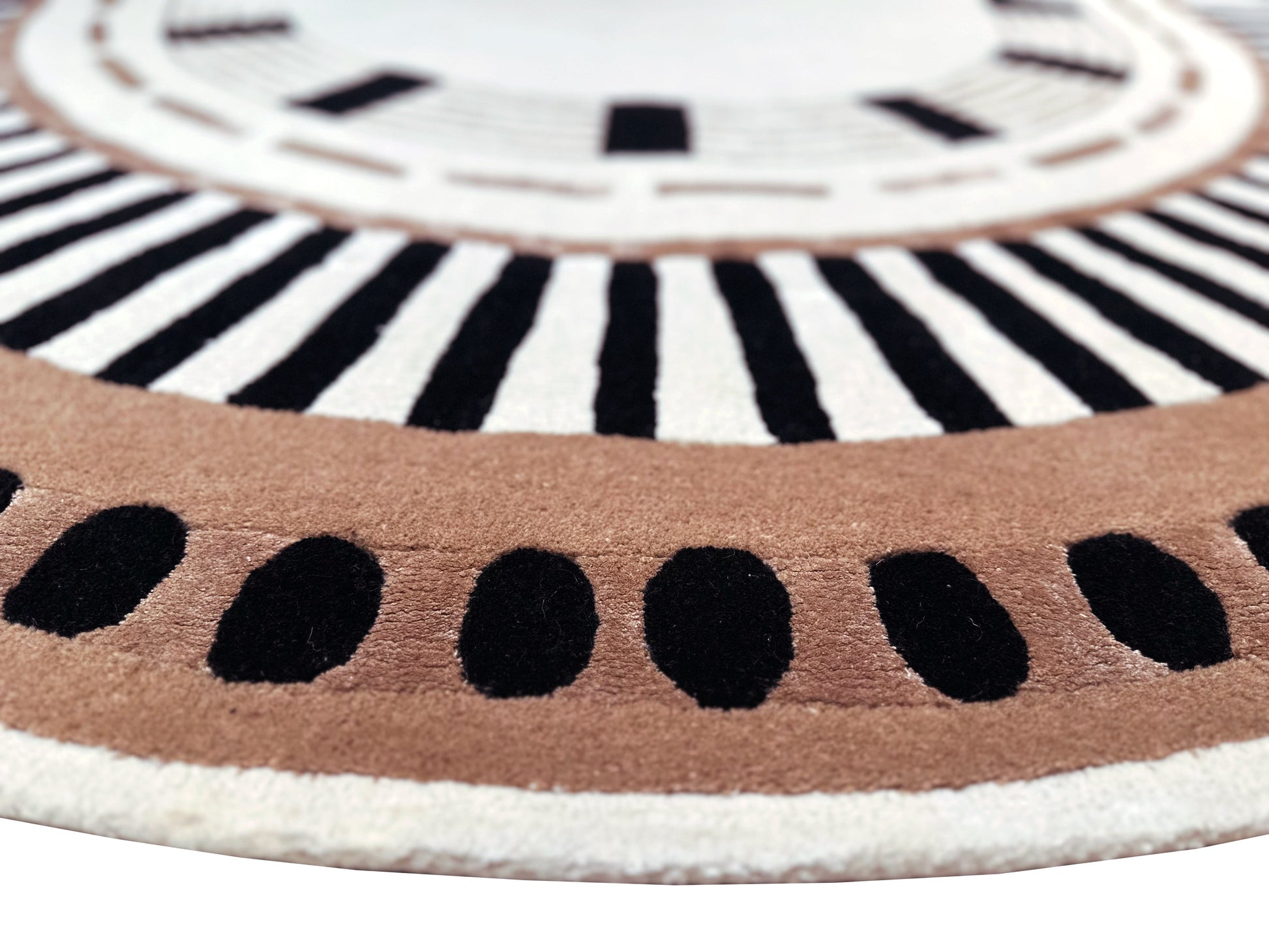 Zoom sur tapis ovale avec tissage touffeté. Relief doux, aspect tactile. Motifs noirs, bruns et ivoire