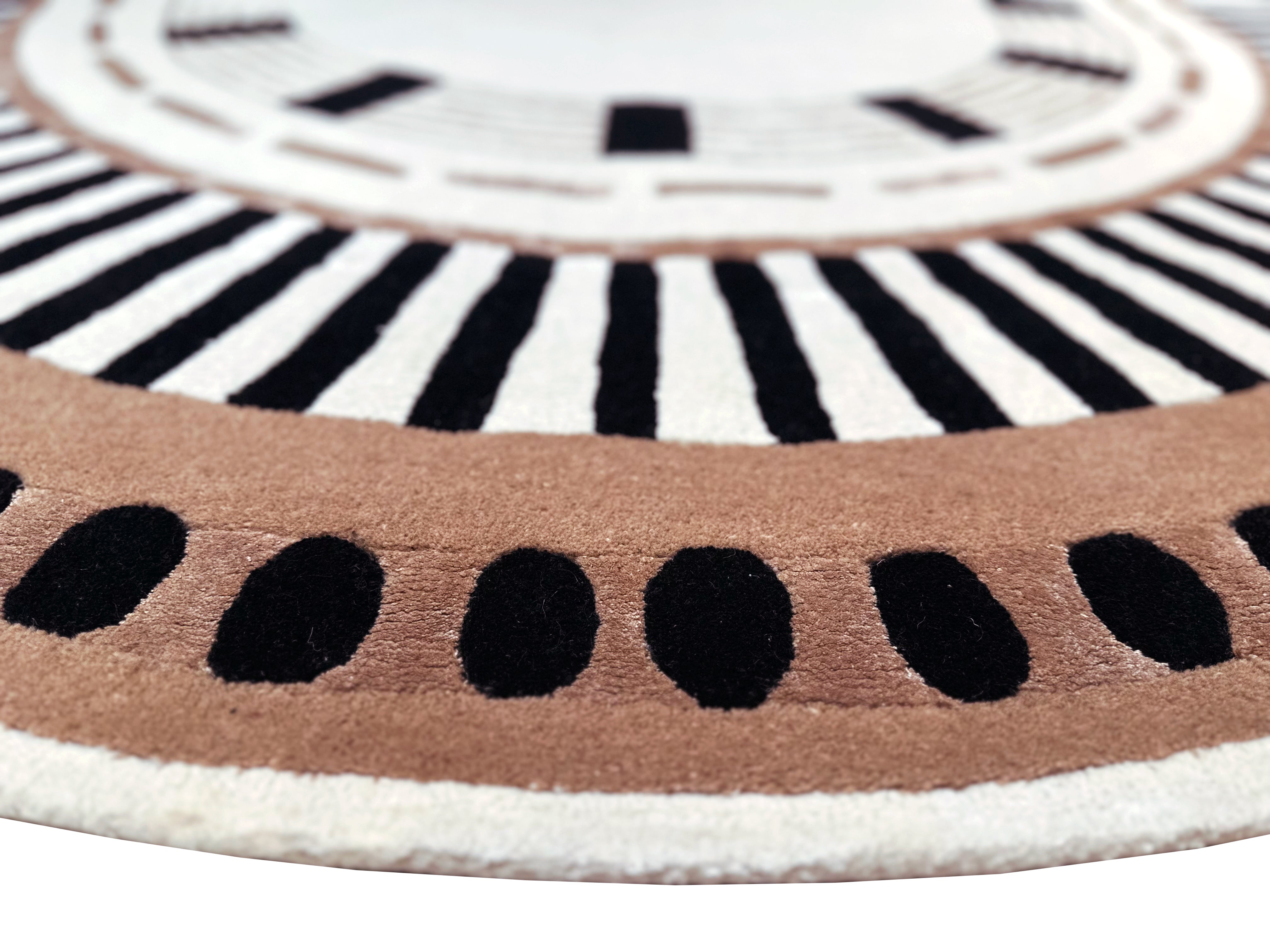 Zoom sur tapis ovale avec tissage touffeté. Relief doux, aspect tactile. Motifs noirs, bruns et ivoire