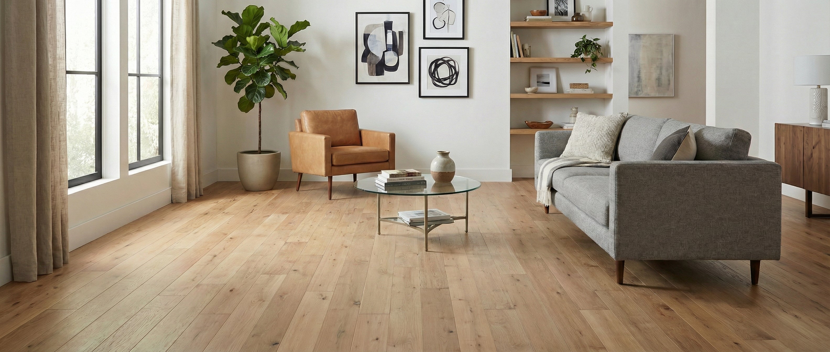 Pièce avec parquet clair, sans tapis. Espace à transformer. Canapé gris, fauteuil cuir, table basse ronde