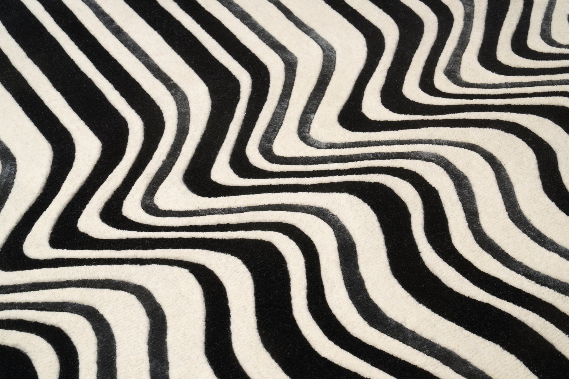 Tapis de type tissage, noir et blanc. Relief ondulé, pièce ovale