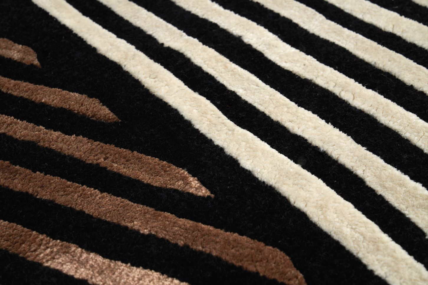 Tapis à rayures diagonales. Tissage touffeté, relief prononcé. Aspect tactile doux et texturé. Noir, beige et marron