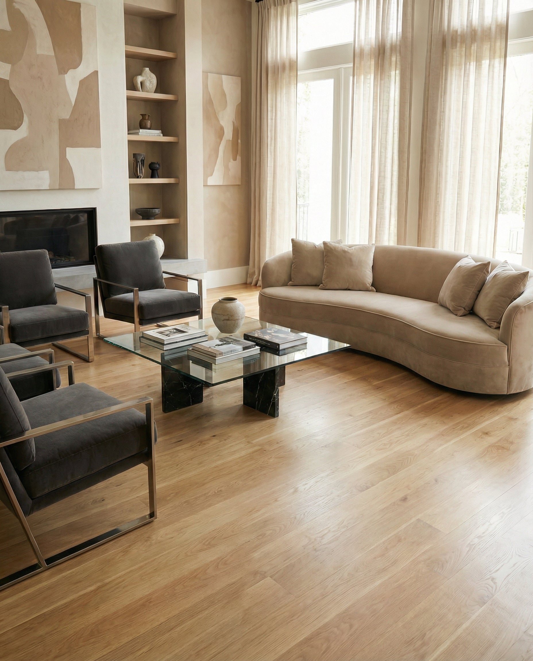 Pièce lumineuse avec plancher en bois clair, canapé beige incurvé, fauteuils gris, table basse rectangulaire, ambiance neutre