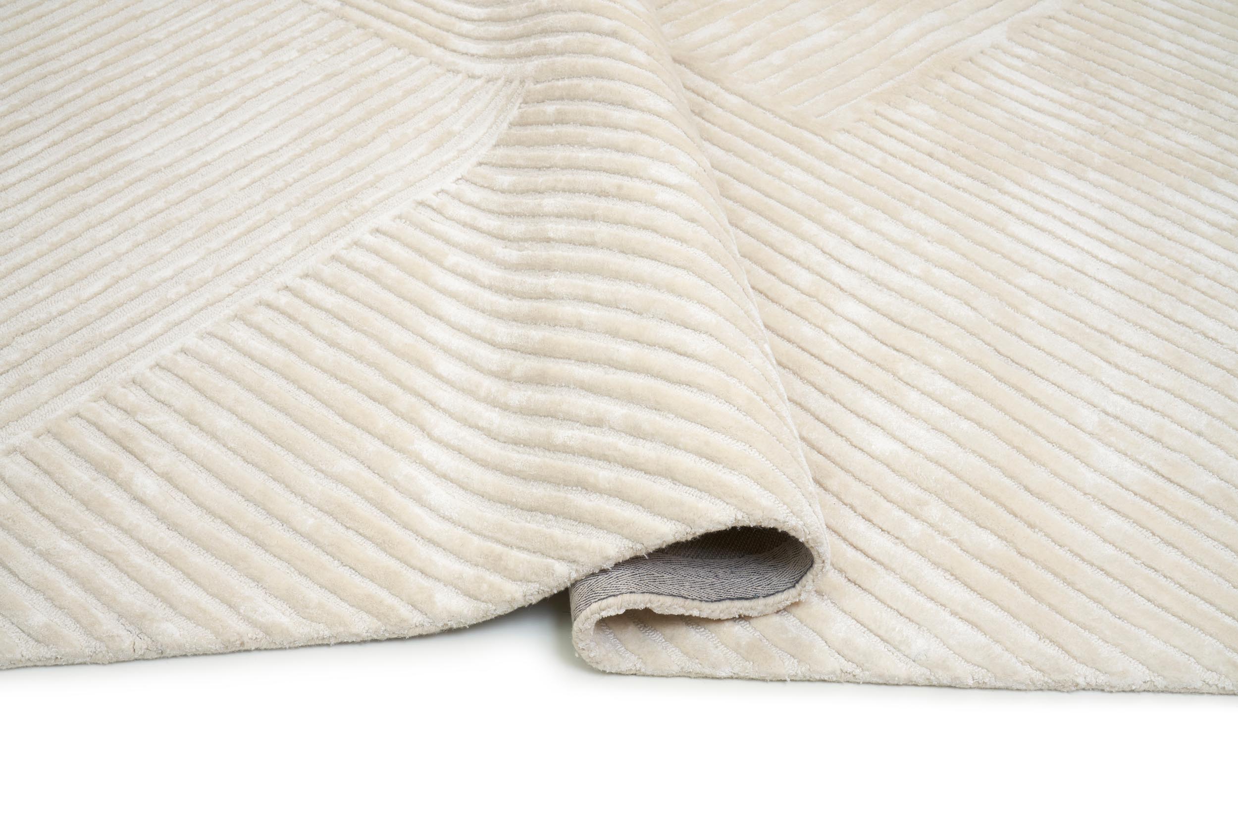 Tapis dense et moelleux, couleur ivoire, pour une pièce confortable. Type tapis avec relief