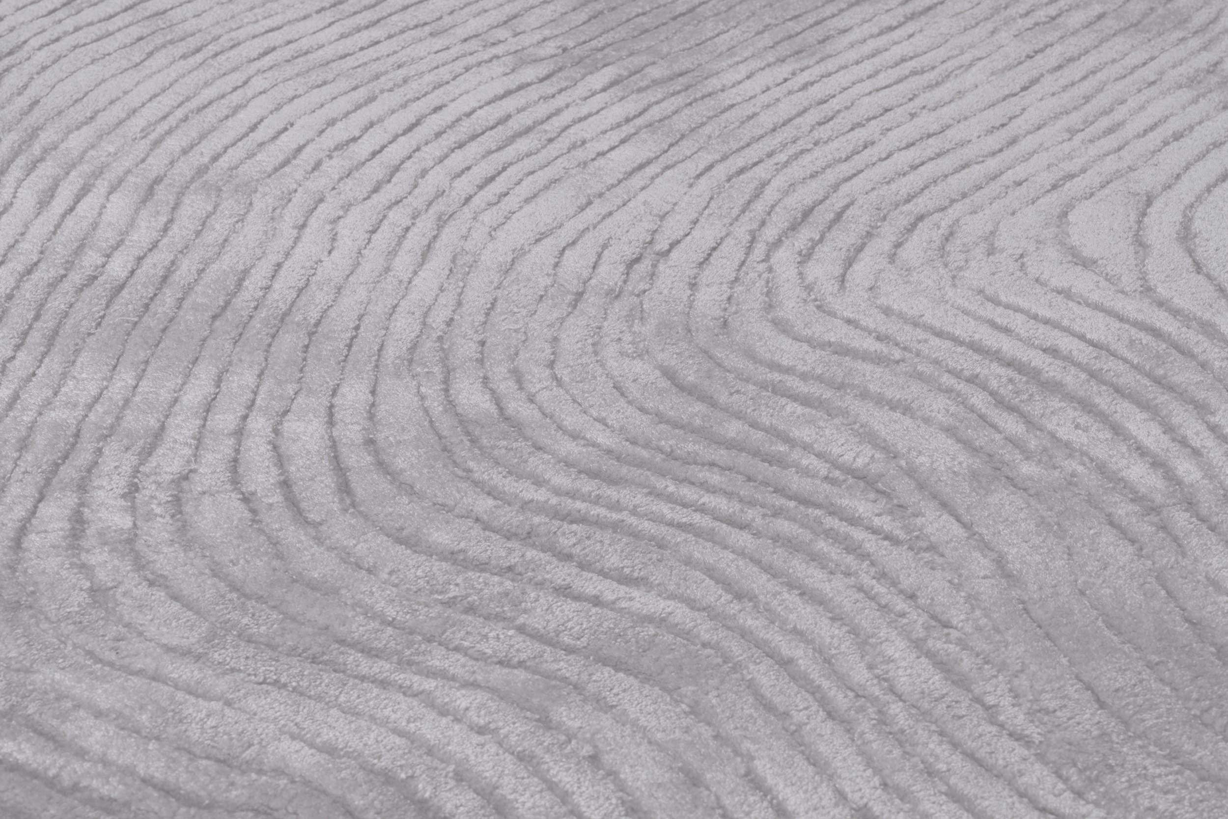 Tapis gris clair avec tissage en relief. Aspect tactile doux et ondulé
