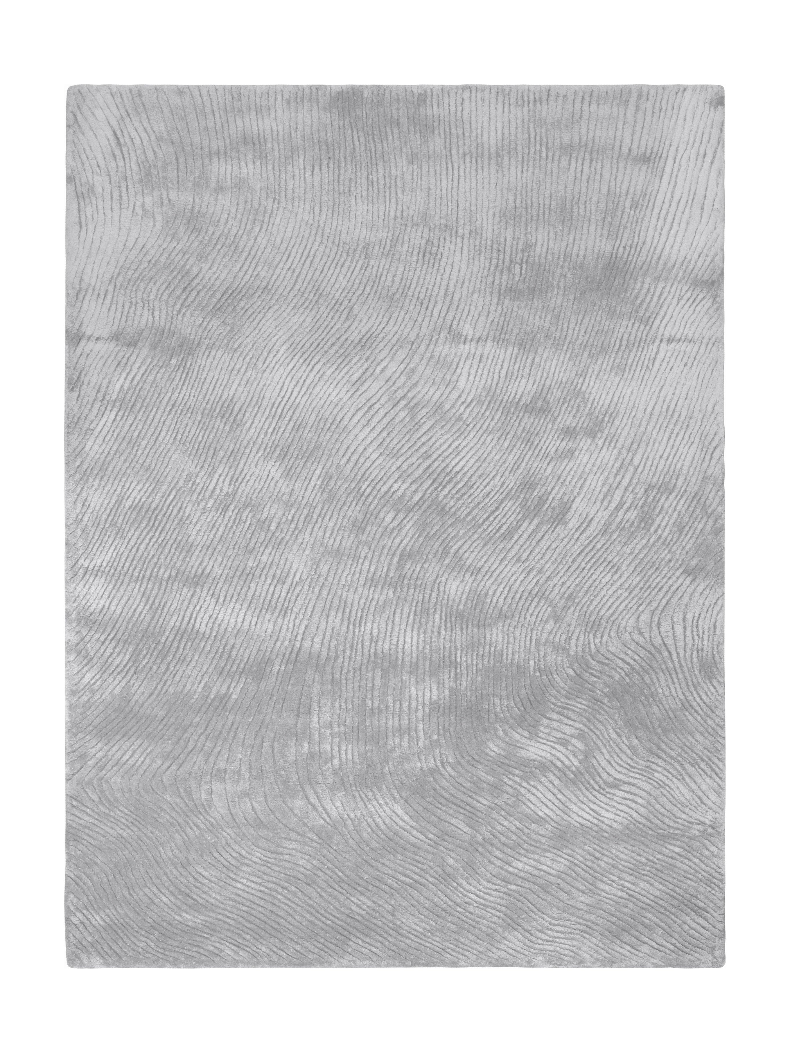 Tapis rectangulaire gris argenté avec un motif de lignes ondulées, créant une ambiance douce et moderne