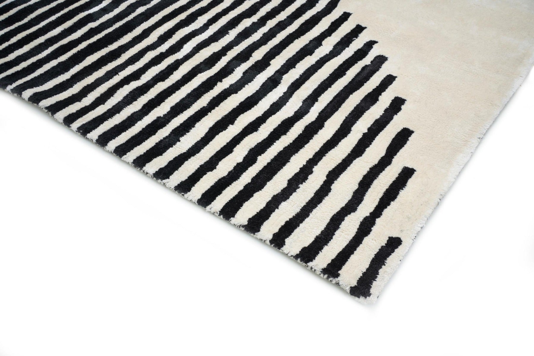 Tapis rectangulaire à rayures noires sur fond ivoire. Finition frangée. Style moderne