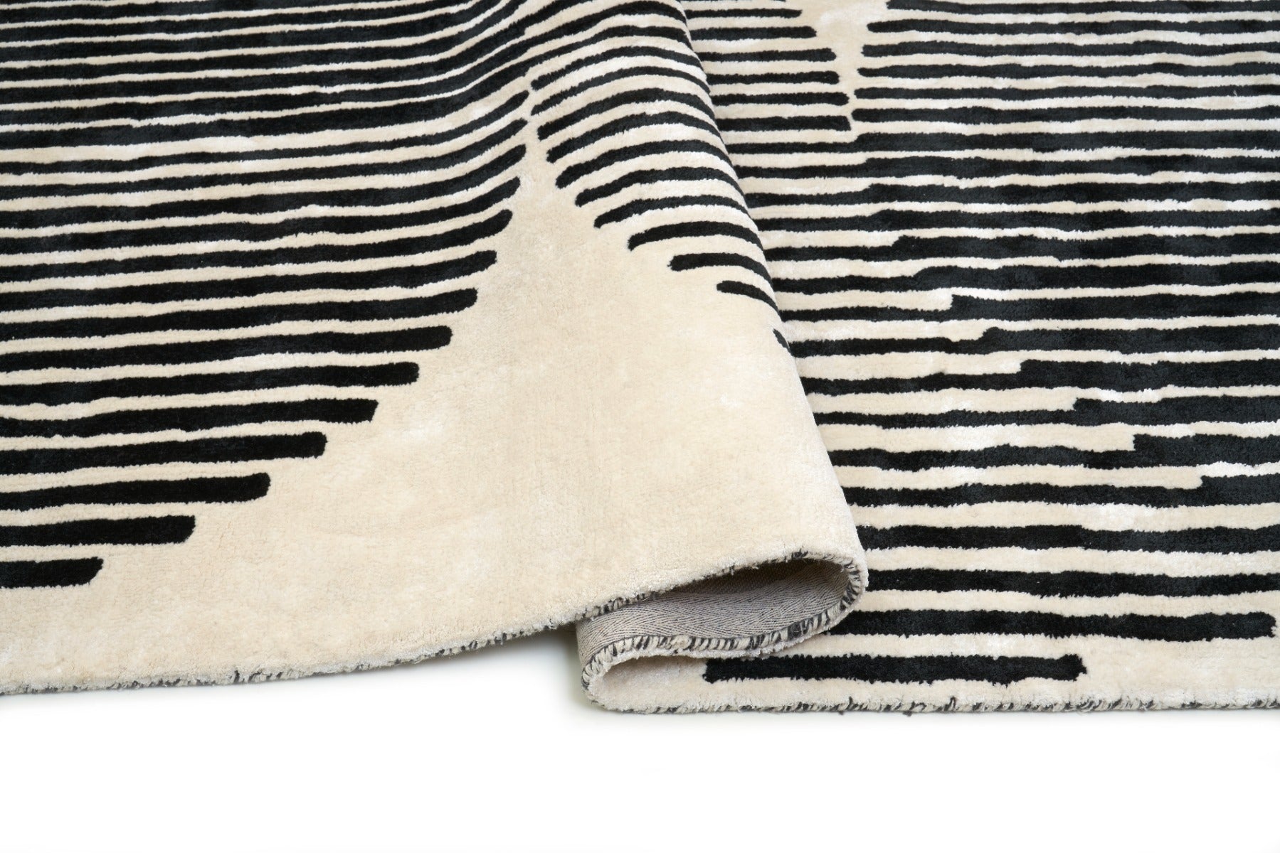 Tapis rectangulaire à rayures noires sur fond ivoire. Apparence dense, moelleuse, confort apparent