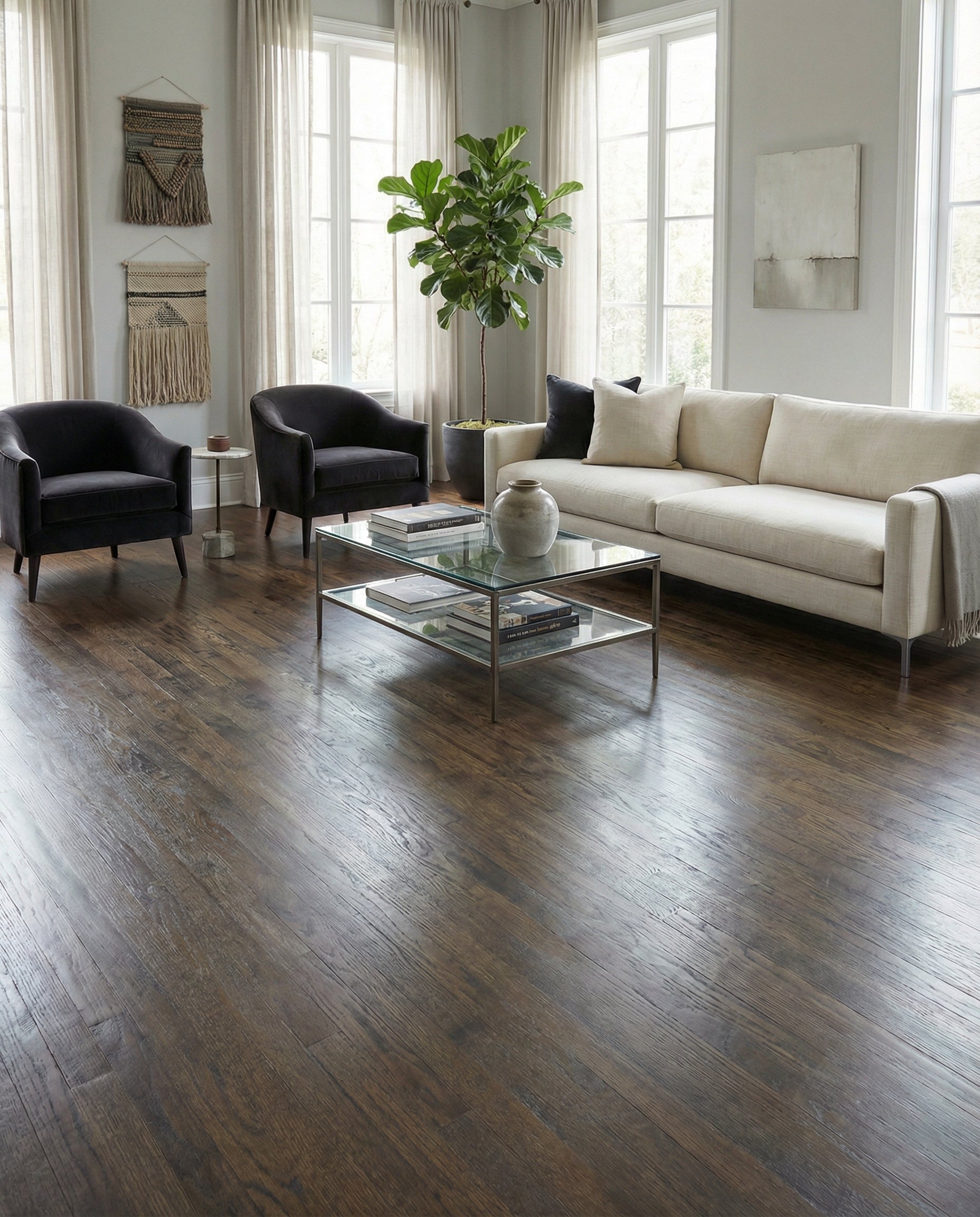 Pièce lumineuse avec plancher de bois foncé, canapé beige, fauteuils noirs, ambiance moderne, espace à transformer