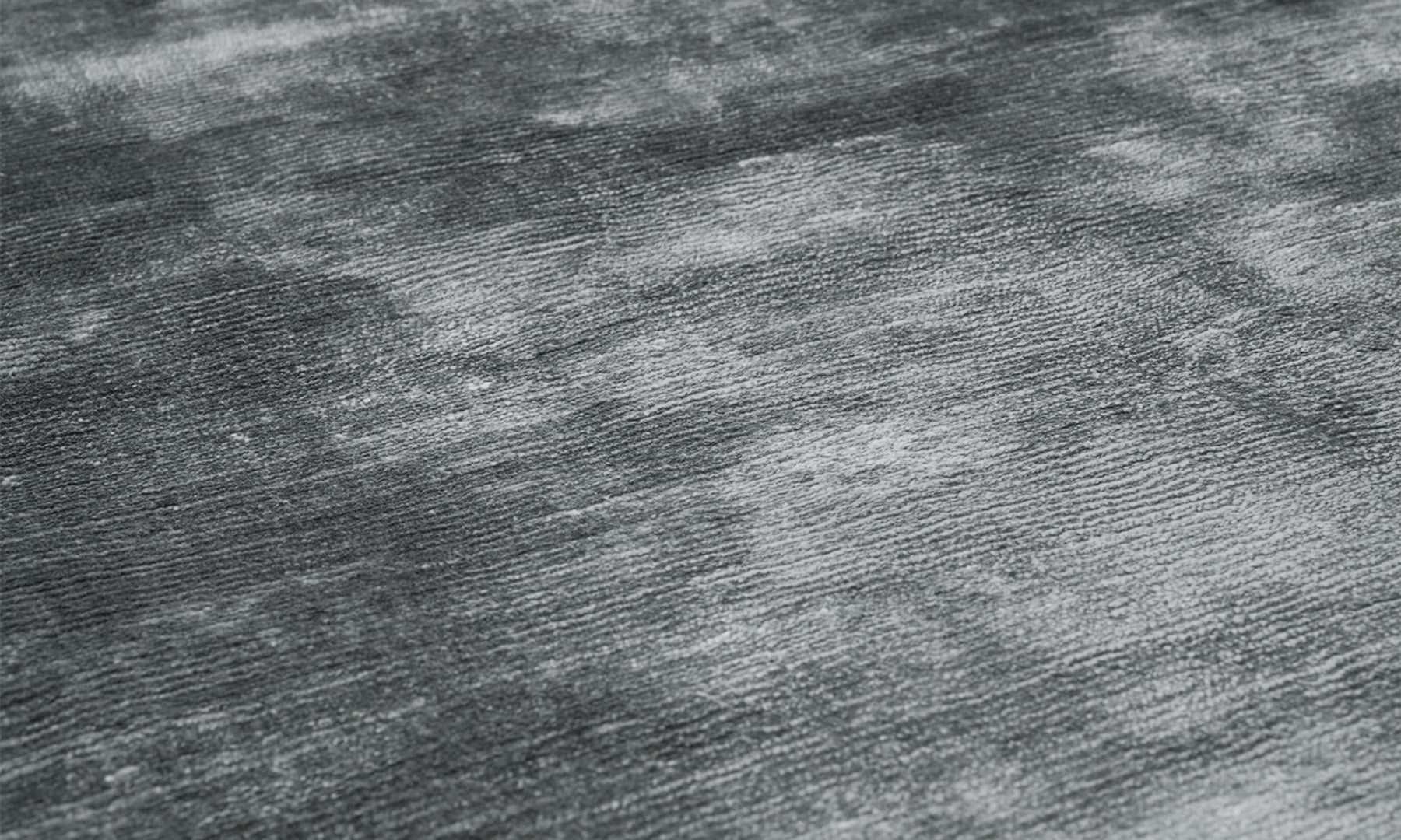 Tapis rectangulaire gris, tissage à lignes horizontales. Relief subtil, aspect tactile du tissu. Ambiance sobre et élégante