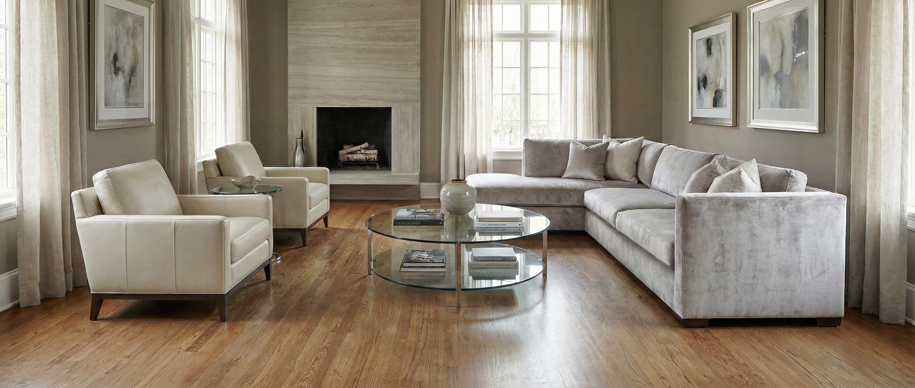 Pièce aux tons neutres, parquet clair. Canapé, fauteuils, table basse ovale. Espace vide pour un tapis, ambiance cosy