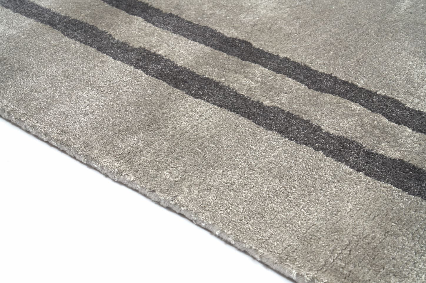 Tapis rectangulaire gris clair, tissage texturé avec bandes foncées. Relief doux, aspect tactile velouté