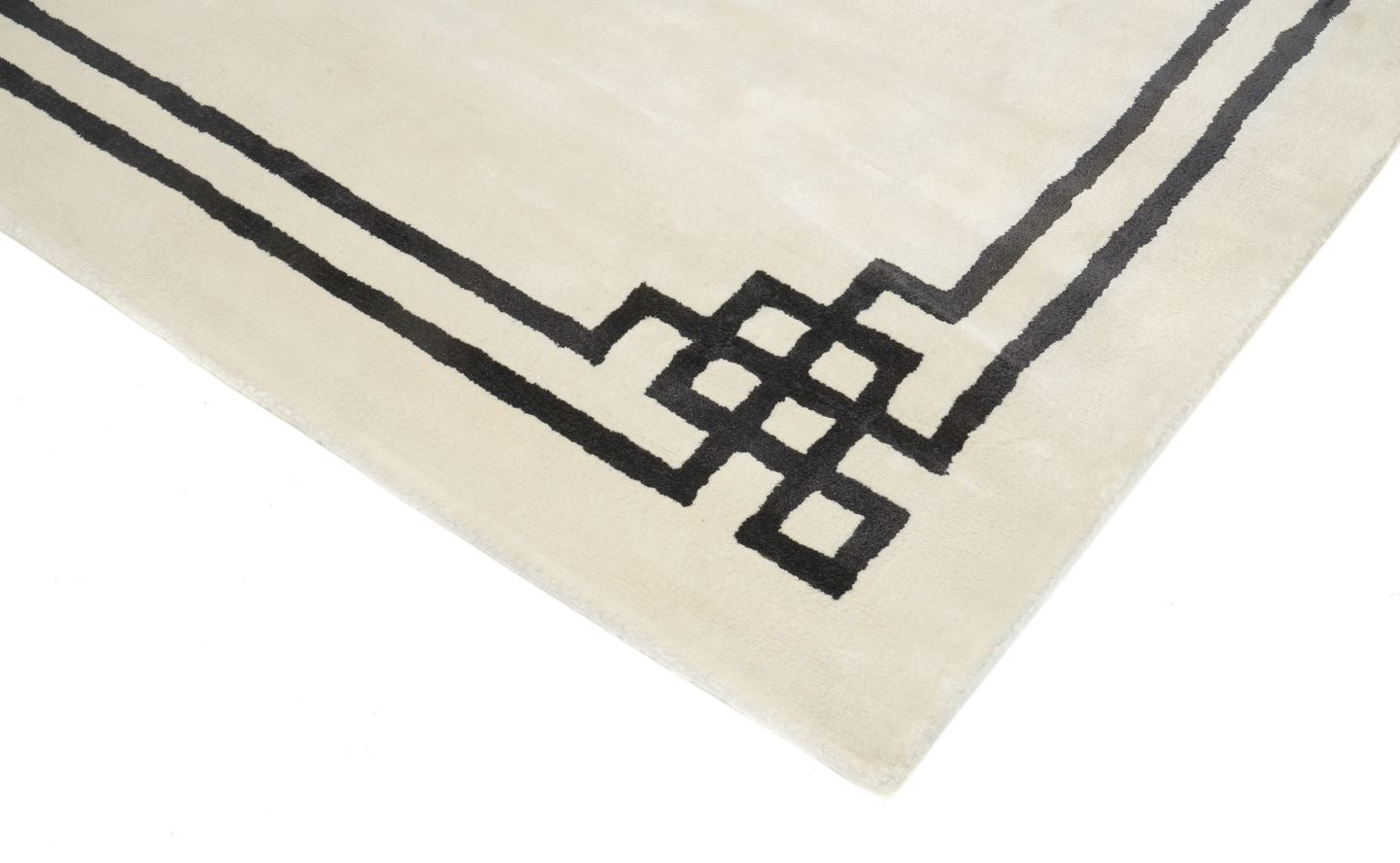 Tapis rectangulaire ivoire avec bordure noire géométrique. Finition de qualité, ambiance moderne