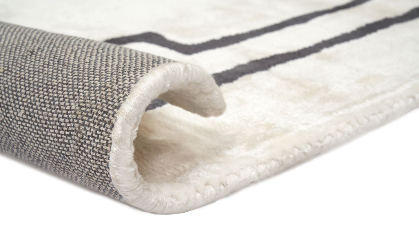 Tapis rectangulaire, tissage texturé. Relief doux, aspect tactile velouté. Couleurs ivoire et noir. Ambiance chaleureuse