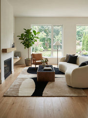 Tapis rectangulaire aux motifs abstraits beige et noir. Design épuré dans un salon au style contemporain