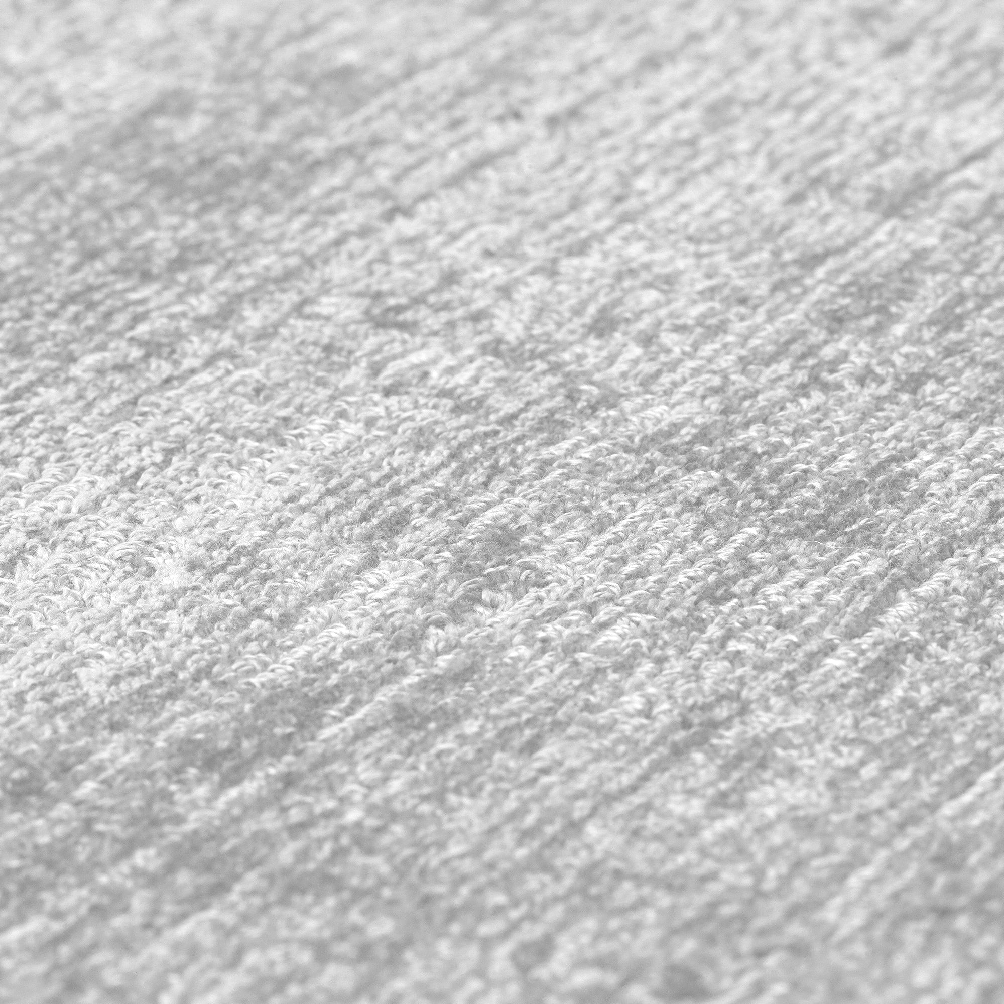 Gros plan d'un tapis en laine gris clair. Tissage en relief, aspect tactile et doux. Texture dense et moelleuse