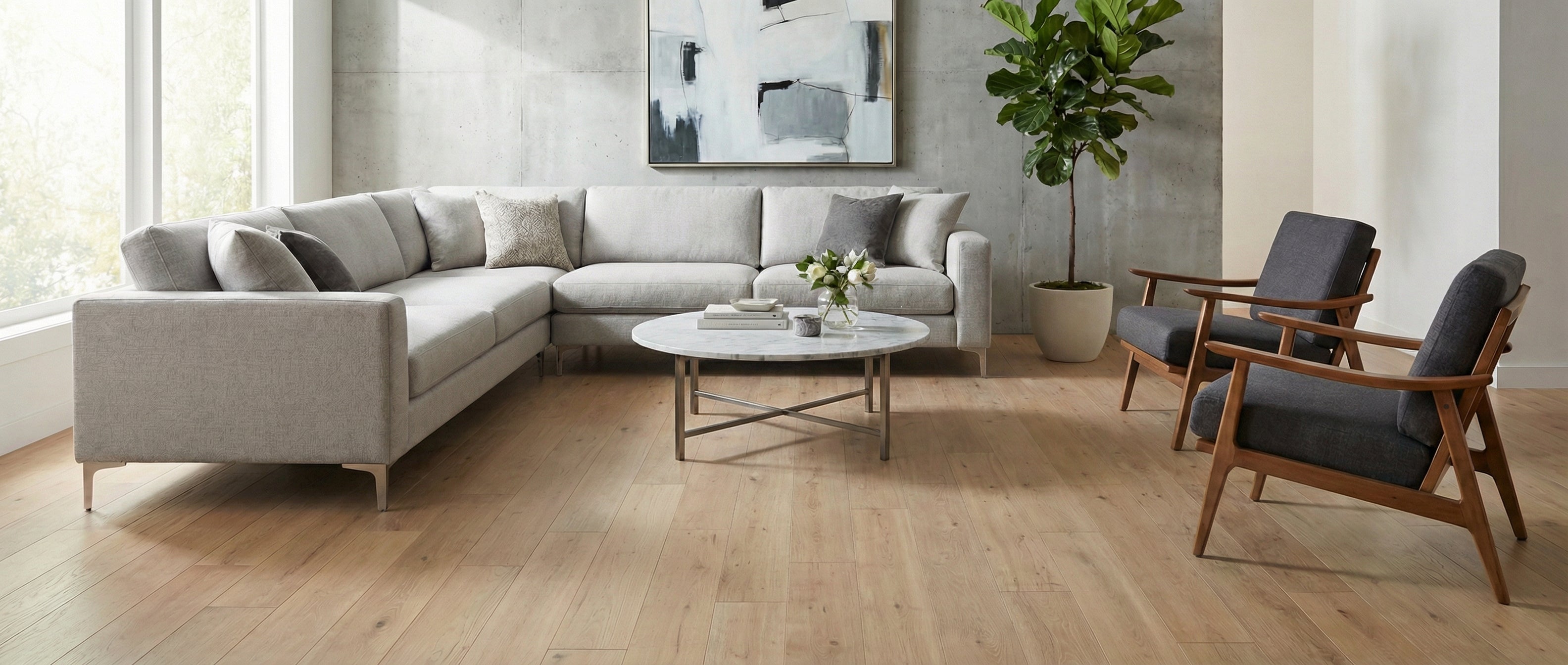 Pièce avec plancher en bois clair, canapé gris, fauteuils. Table ronde. Espace à transformer pour un tapis