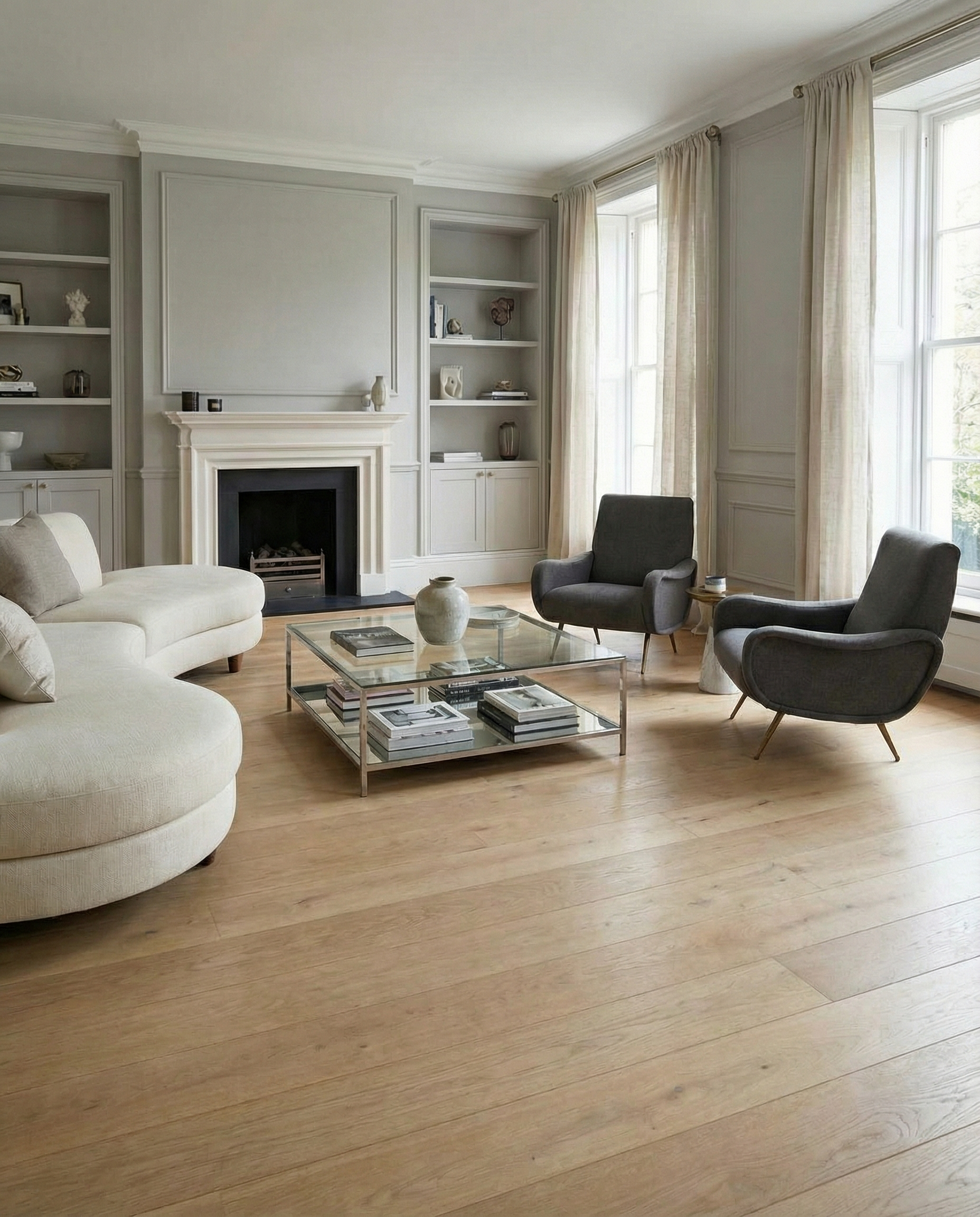 Pièce avec potentiel, sans tapis. Sol clair, deux fauteuils gris. Canapé rond, murs gris clair