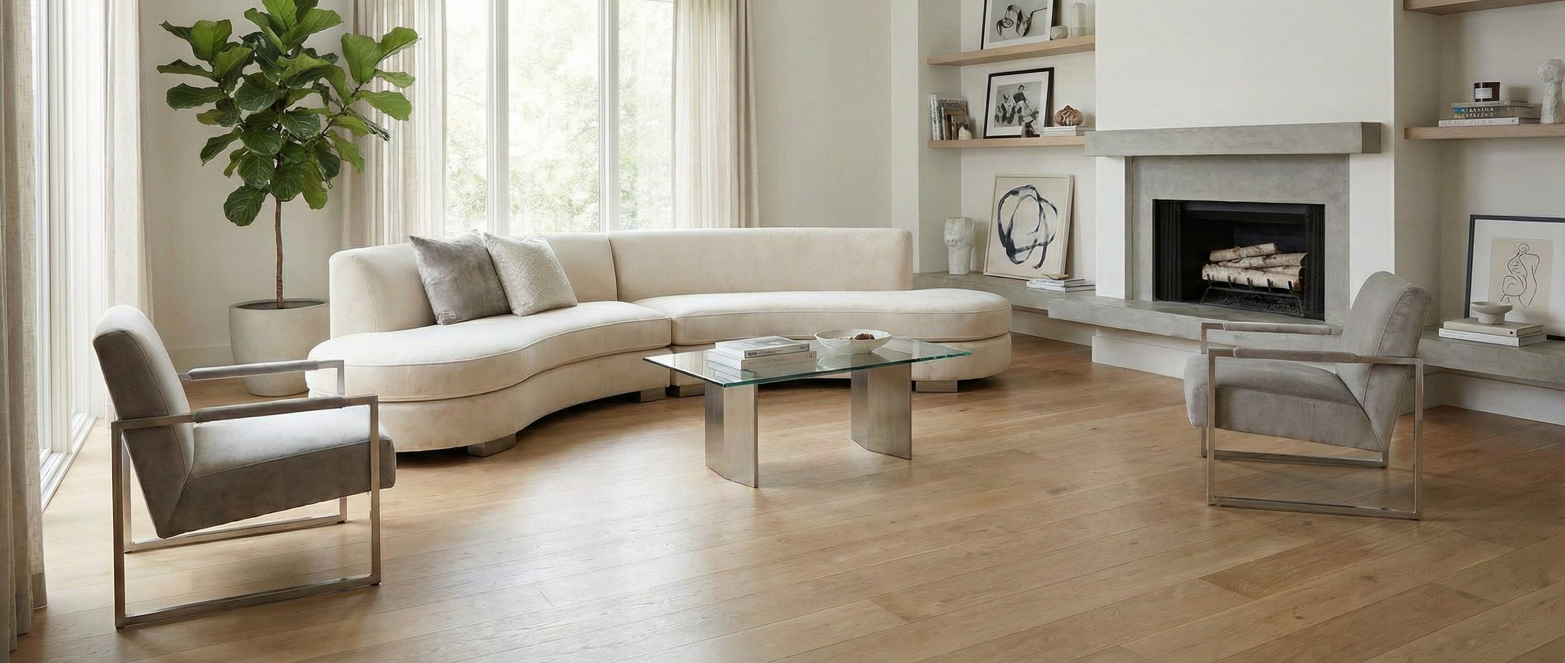 Pièce lumineuse avec canapé incurvé, fauteuils gris, cheminée. Sol en bois clair. Espace vide, potentiel déco