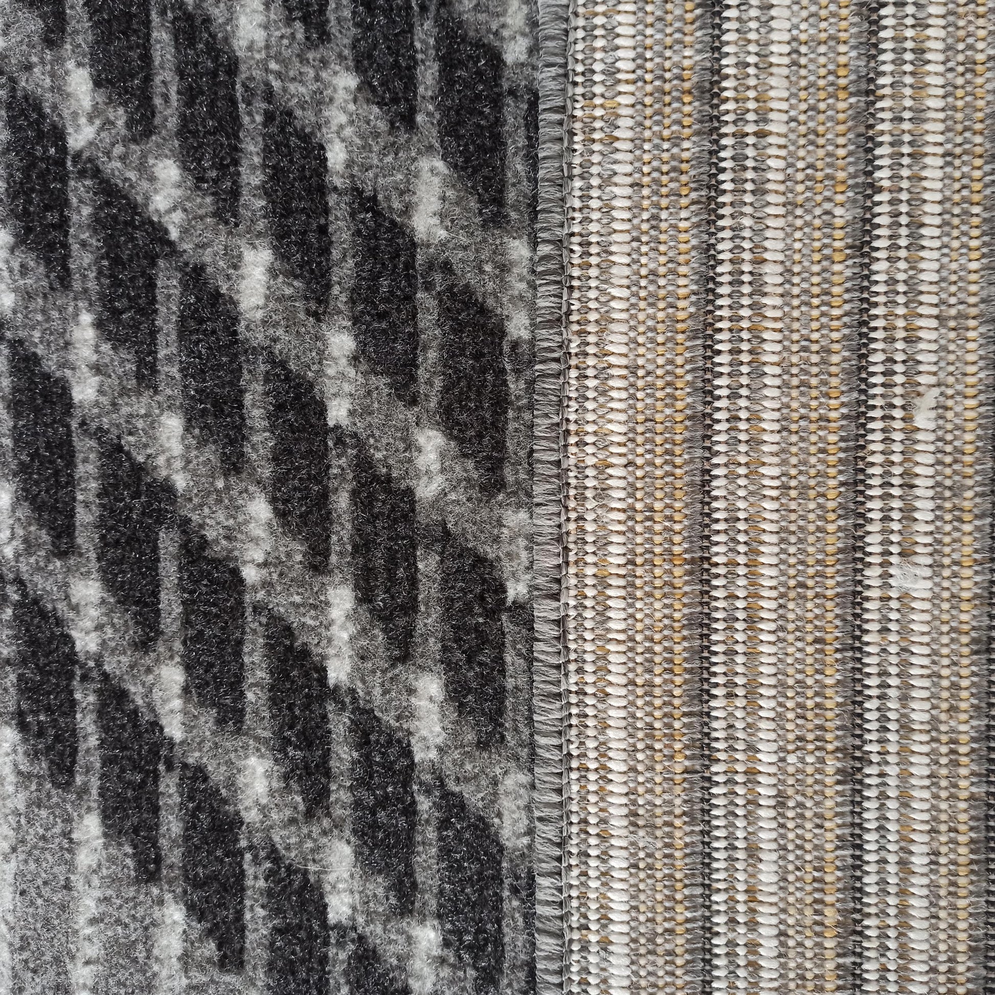 Tapis au motif abstrait noir et gris sur une texture à poils longs, juxtaposé à un tissage rayé beige, gris et blanc
