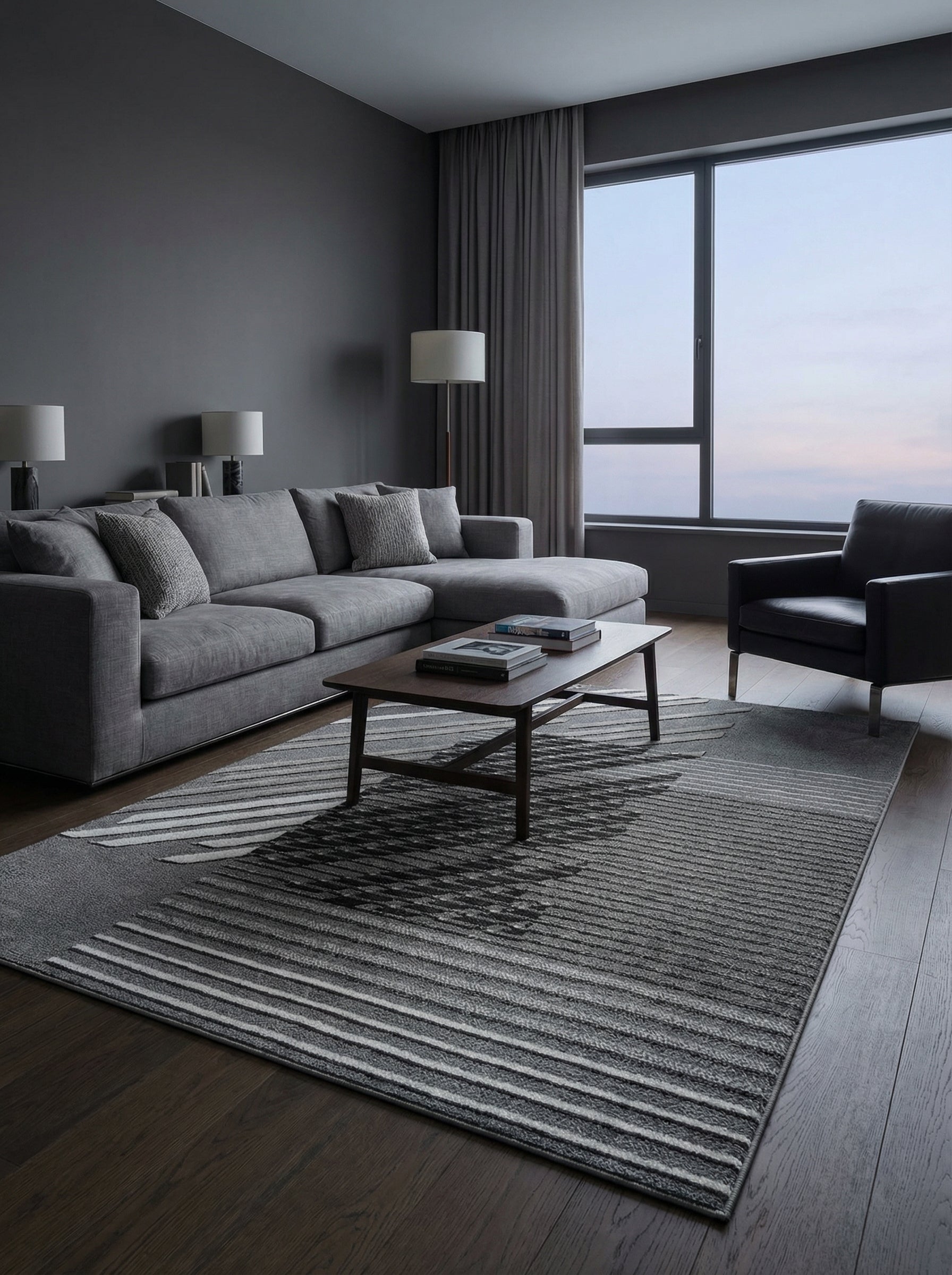 Tapis rectangulaire aux motifs géométriques gris et noirs, avec des rayures claires et foncées, posé sur un parquet sombre dans un salon moderne