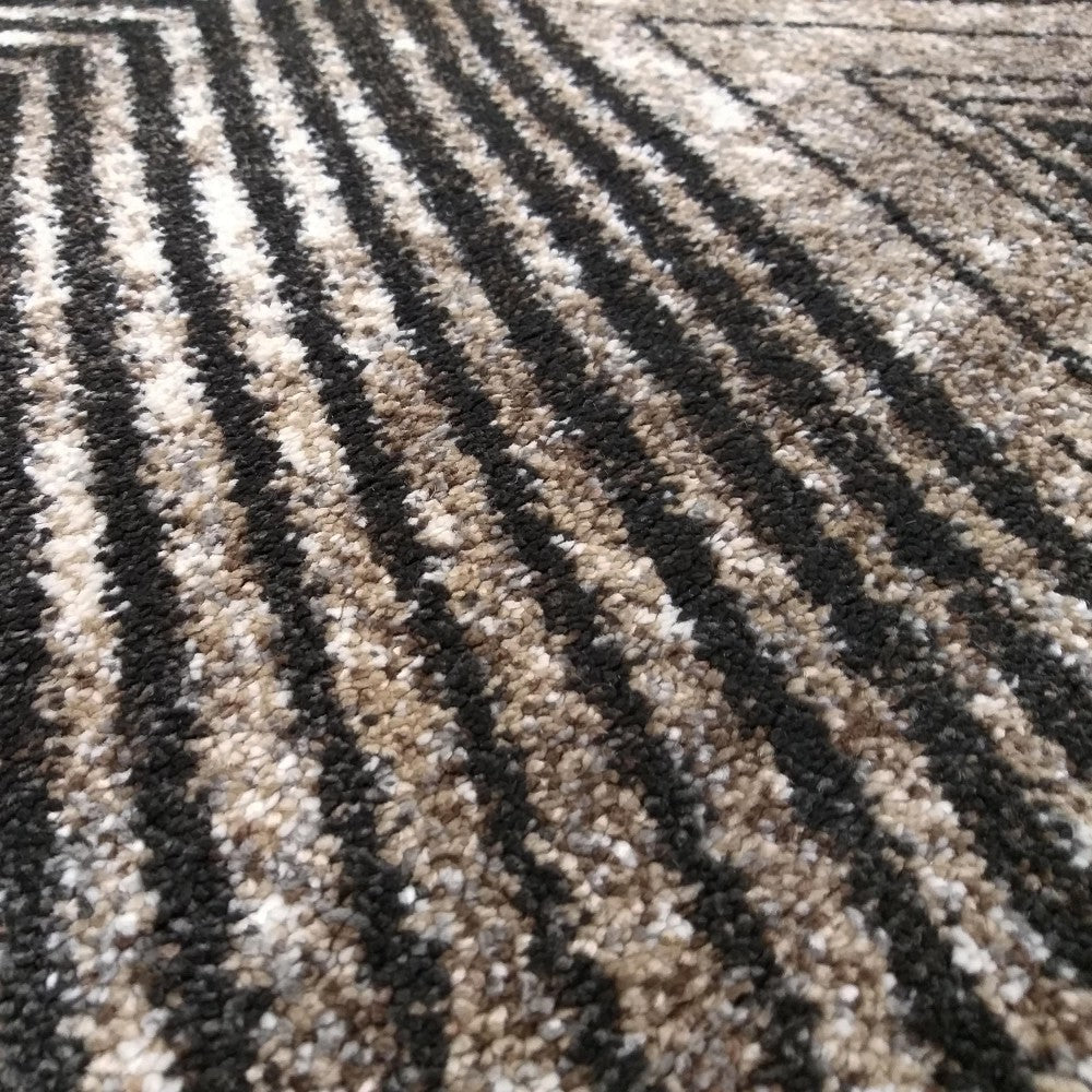 Tapis à poils longs avec un motif géométrique composé de bandes noires sur un fond mélangé de beige, brun et blanc