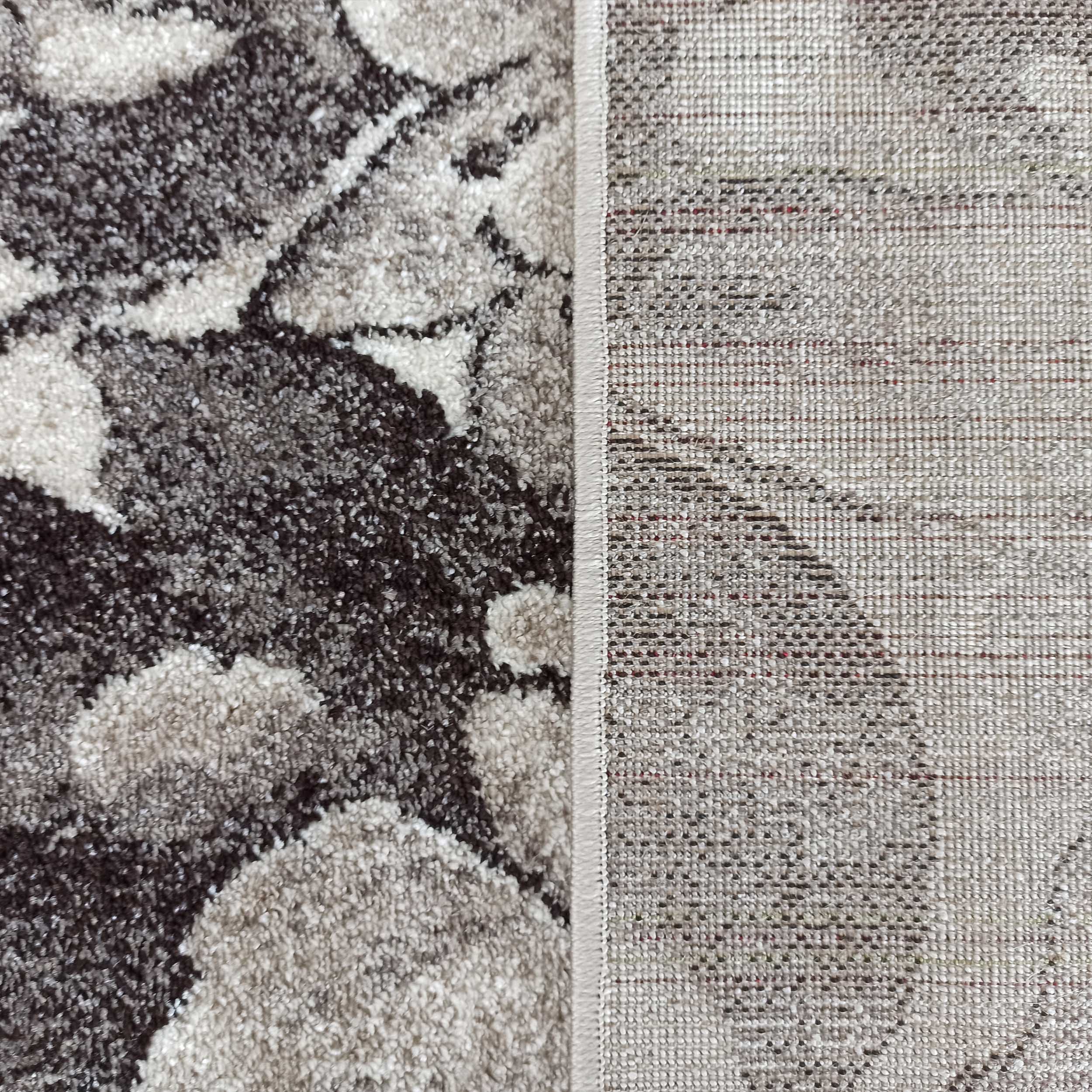 Tapis texturé aux motifs abstraits gris, beige et marron foncé avec une bordure cousue et un dessous tissé clair