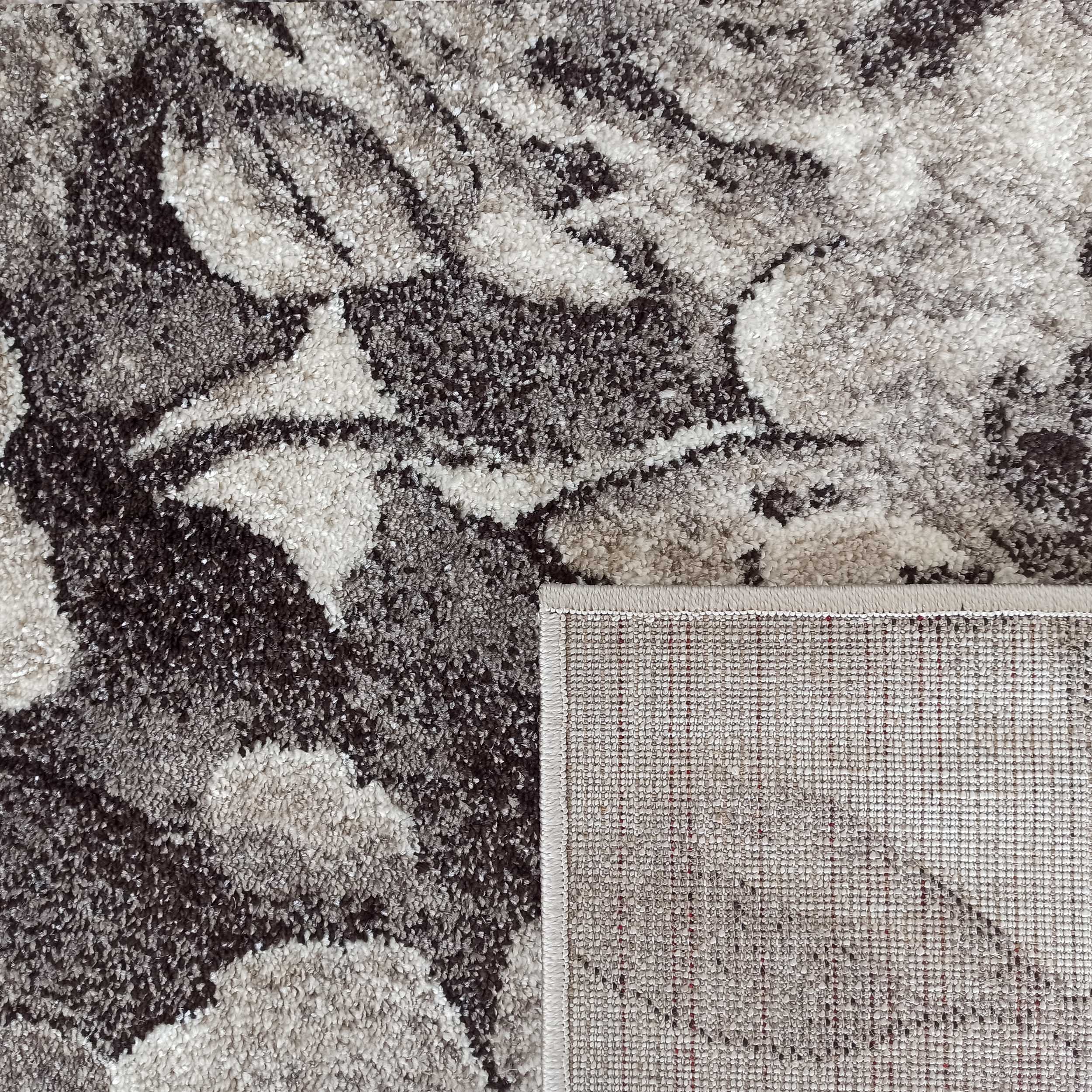Tapis moelleux aux motifs abstraits gris, marron, beige et blanc cassé, avec un coin replié montrant le revers tissé