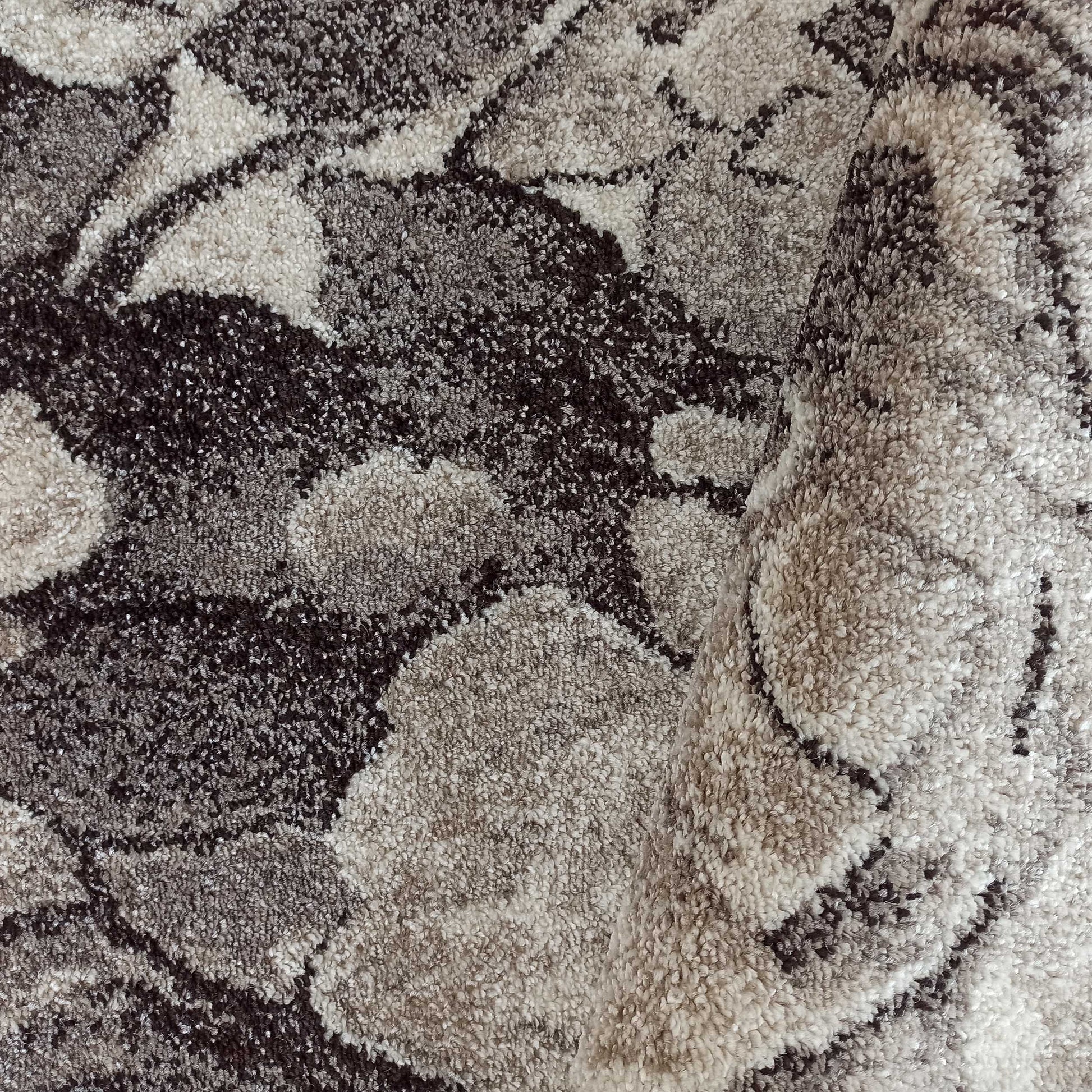 Tapis moelleux aux motifs abstraits dans des tons de gris, marron et beige, légèrement roulé