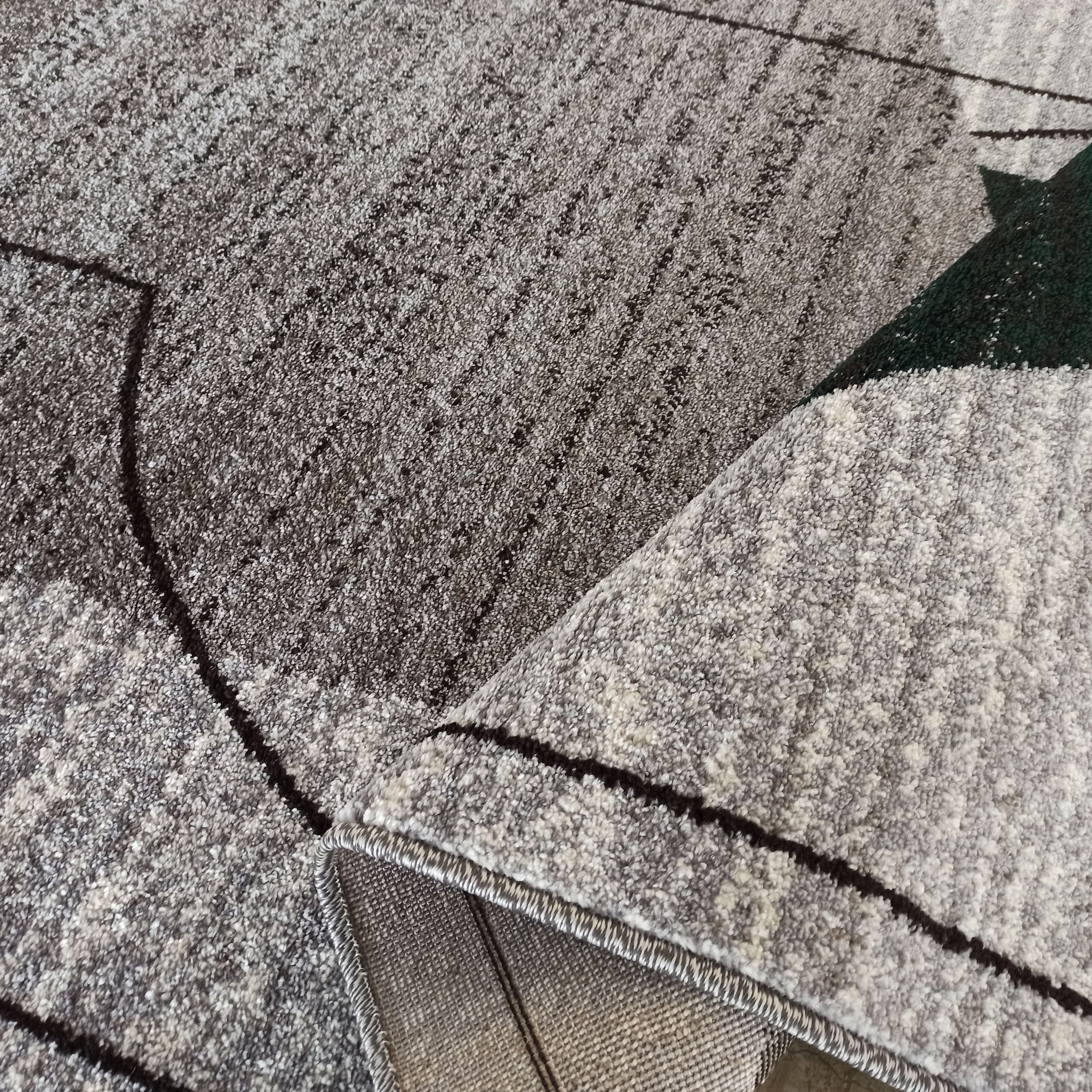 Tapis doux et moelleux aux nuances de gris et vert, avec des lignes sombres formant des motifs abstraits. Le dos tissé est visible
