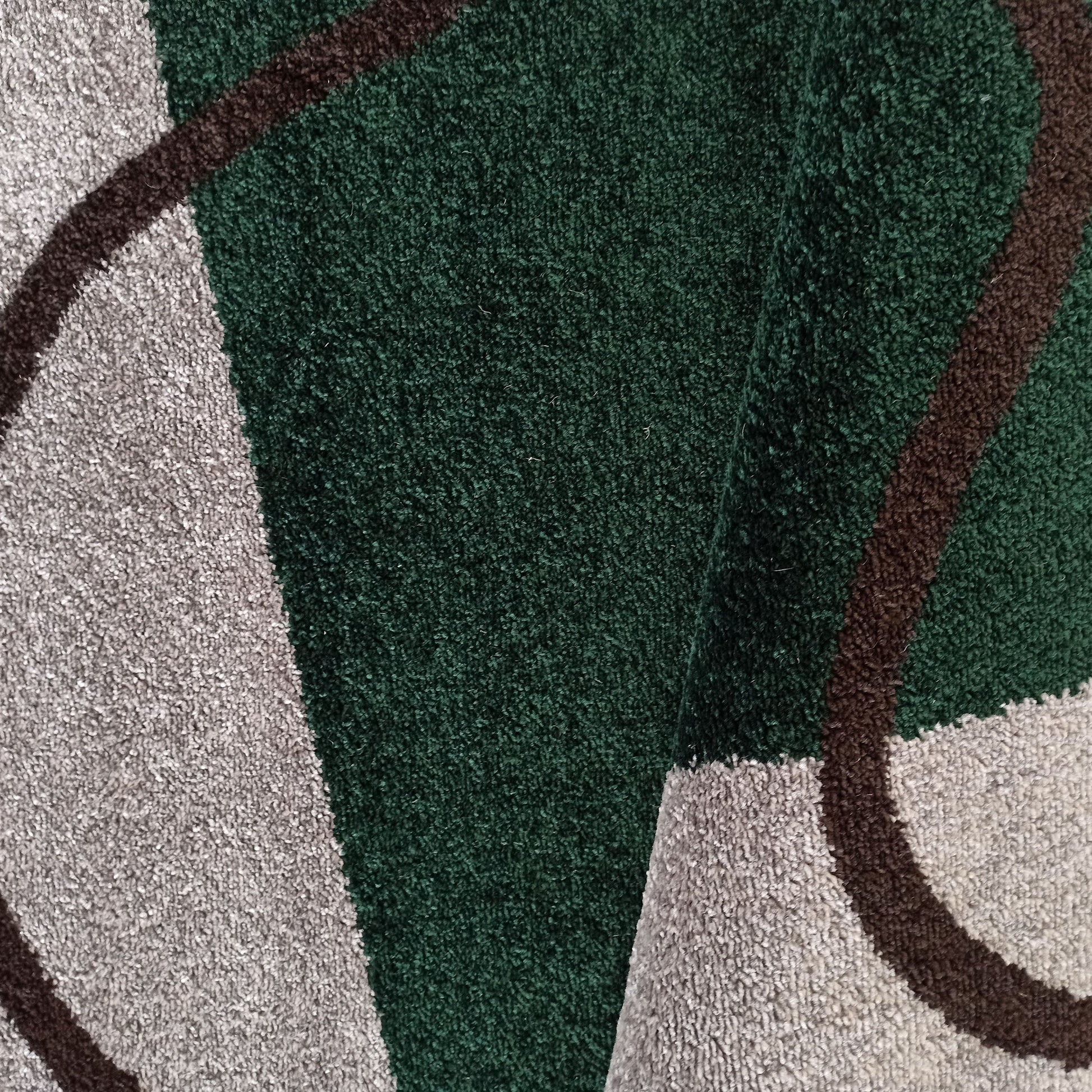 Tapis à poils courts vert foncé, gris clair et marron, avec un motif abstrait de lignes courbes