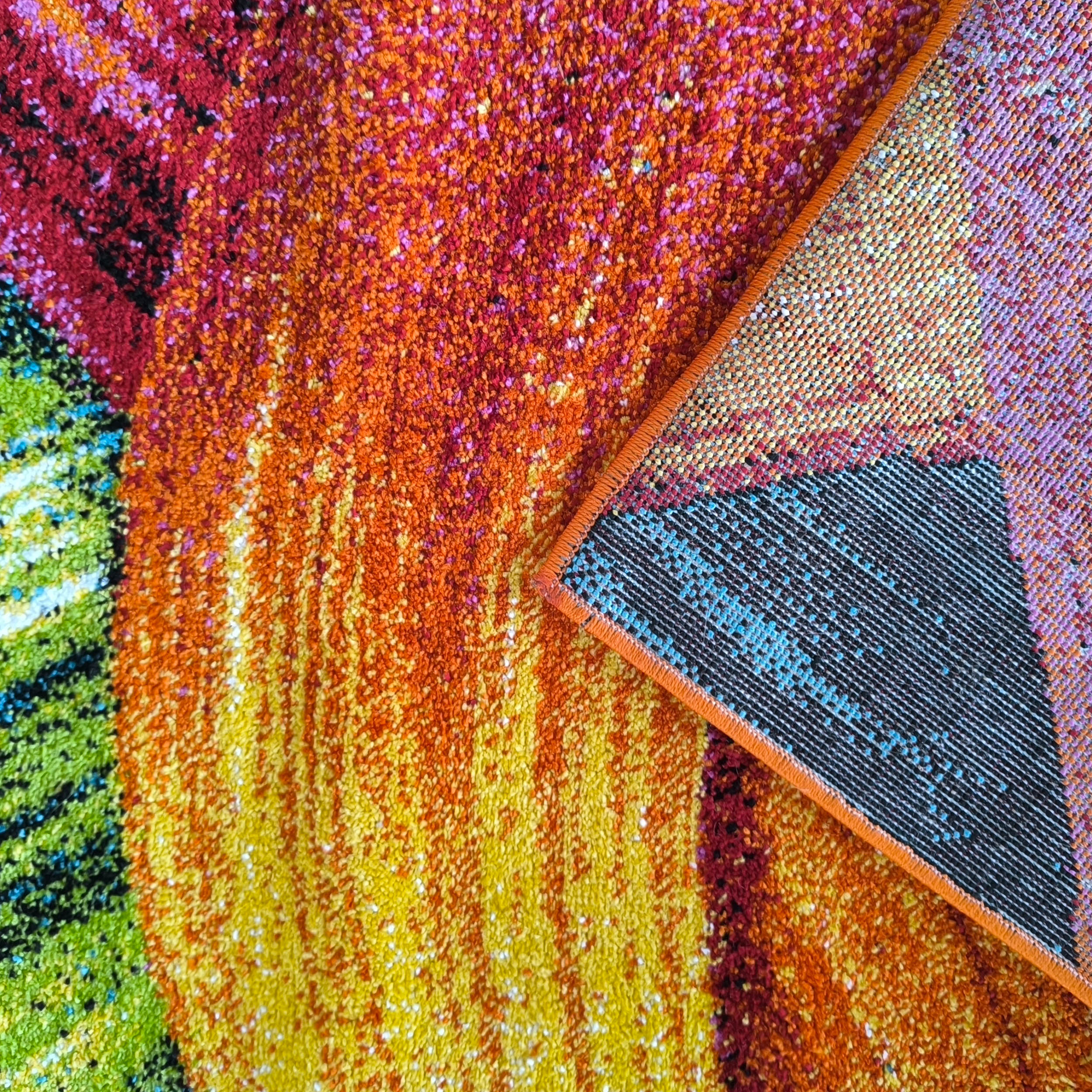 Tapis coloré à motifs abstraits rouge, orange, jaune et vert. Un coin est relevé, montrant son dessous tissé et le bord orange surjeté