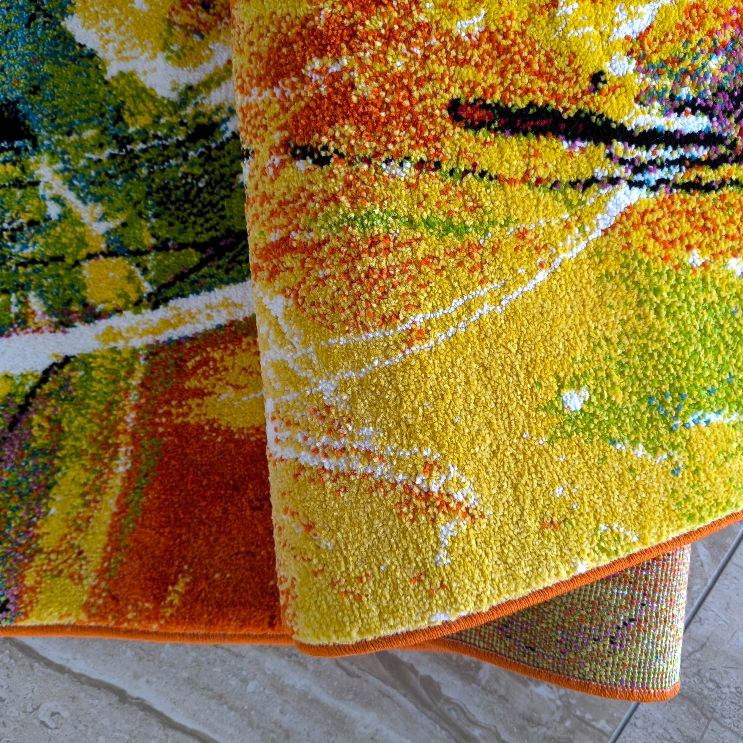 Tapis textile roulé, aux motifs abstraits mouchetés multicolores : jaune, orange, vert, blanc, bleu et noir