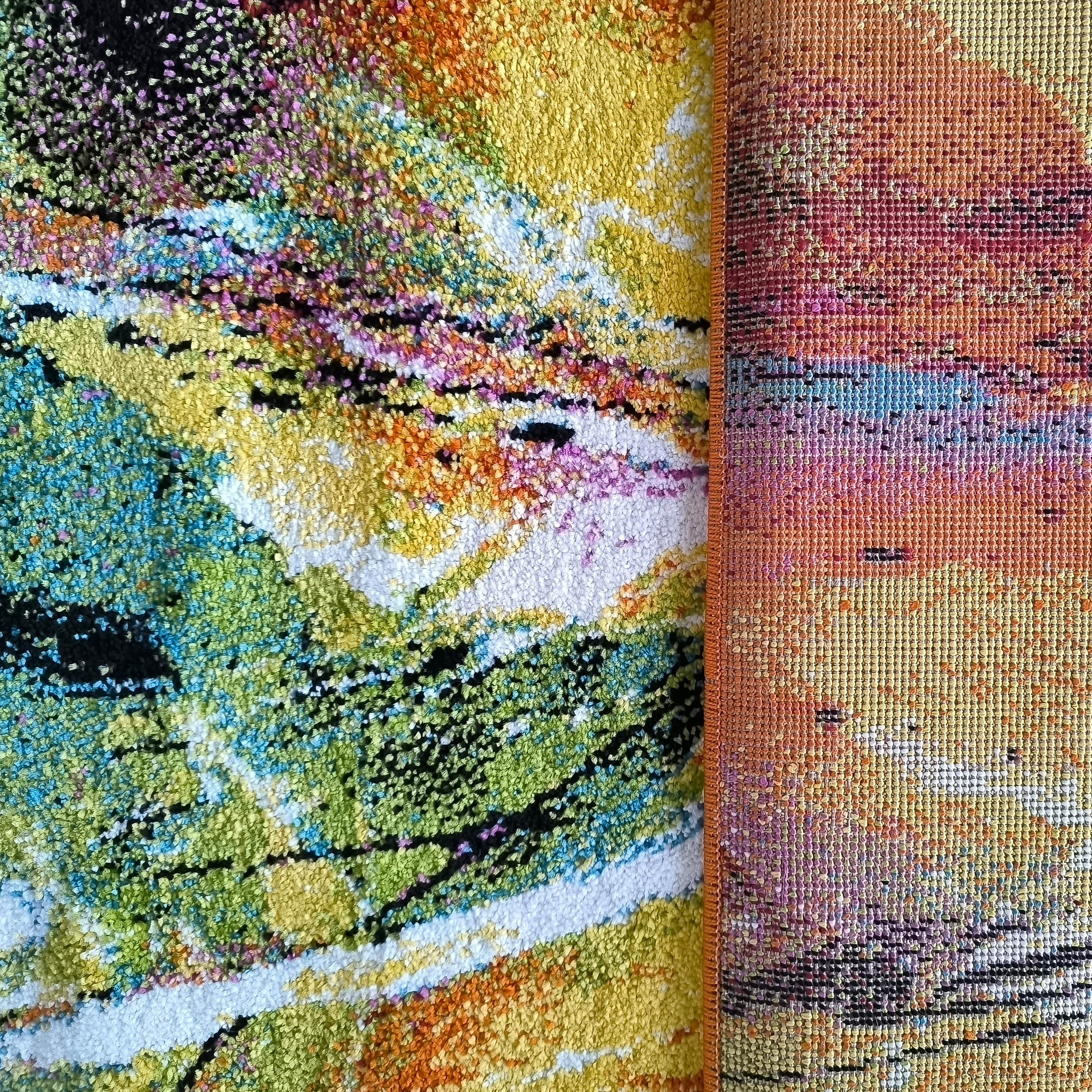 Tapis aux motifs abstraits et texture touffue, avec du jaune, vert, bleu, rose et noir, et un bord tissé orange et rouge