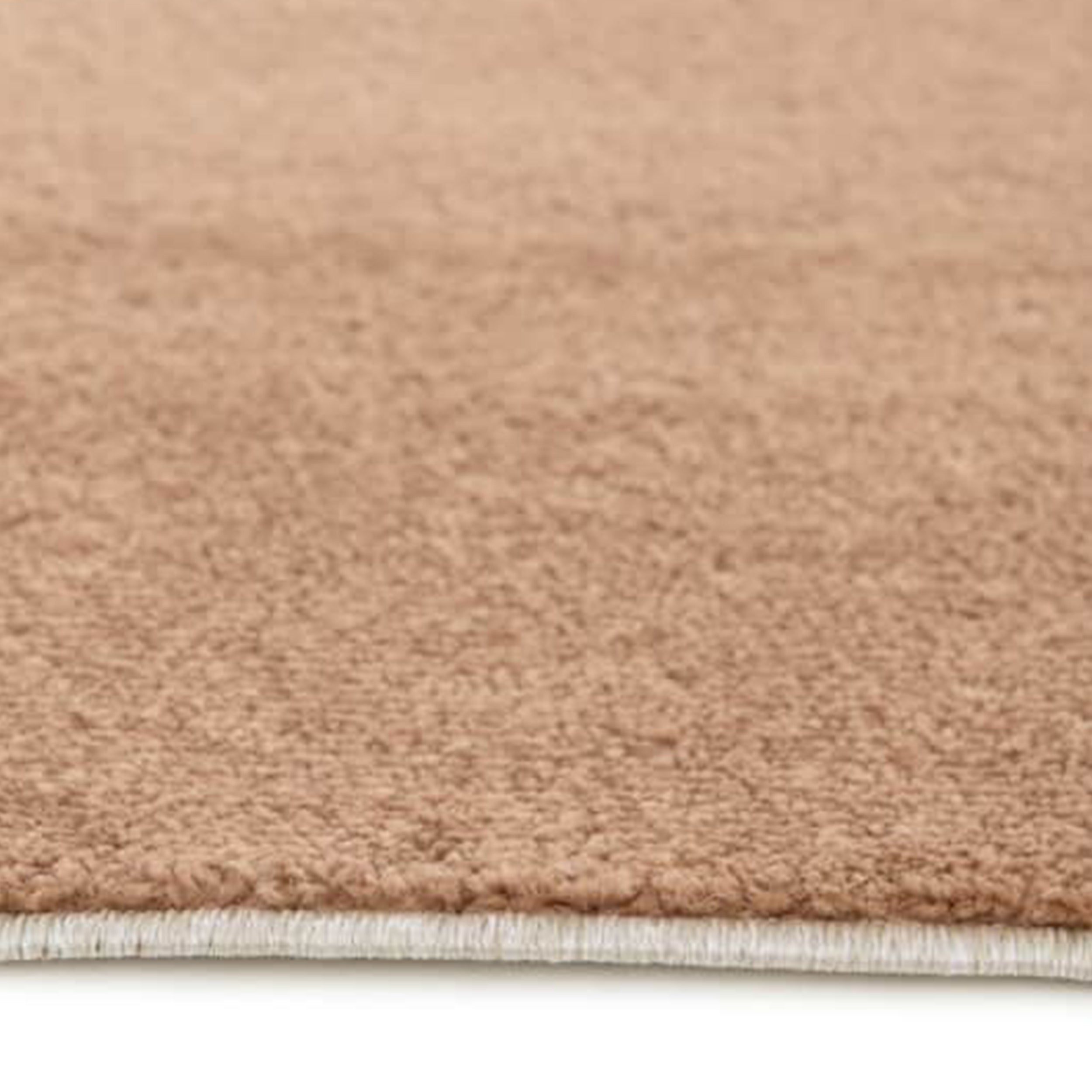 Gros plan sur un tapis uni de couleur beige clair avec une texture douce et moelleuse, et une bordure claire