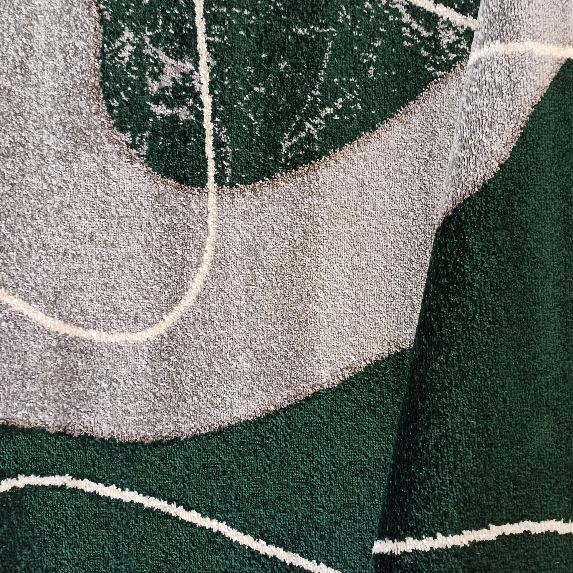 Tapis texturé vert foncé et gris clair avec des motifs abstraits et des lignes blanches incurvées