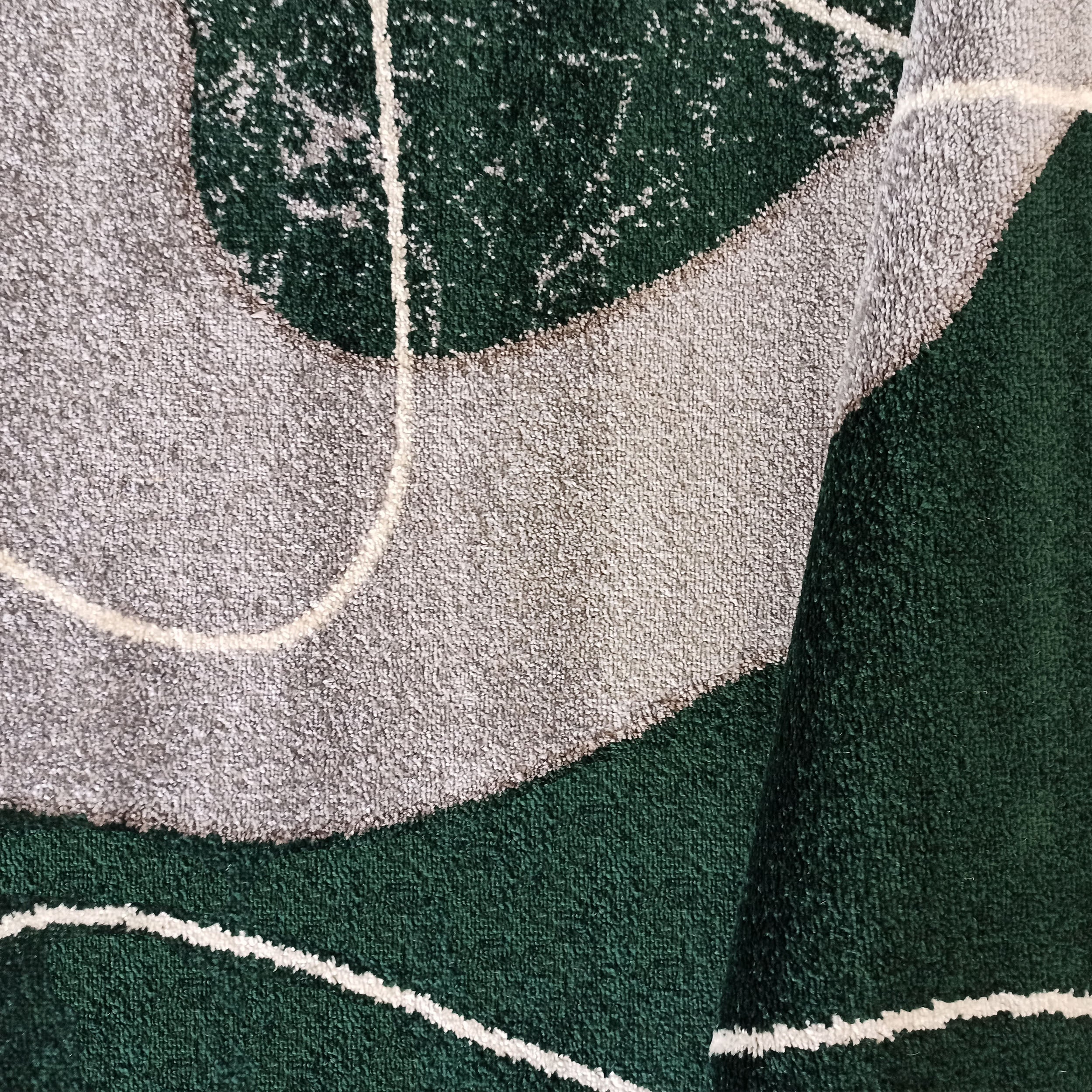 Tapis texturé vert foncé et gris clair avec des motifs abstraits et des lignes blanches incurvées