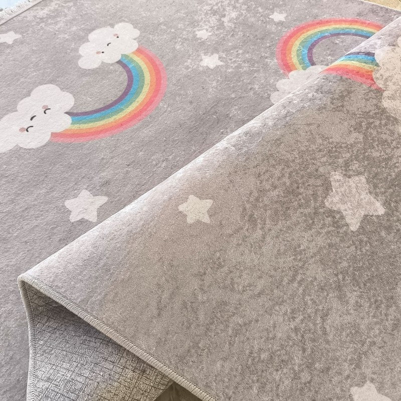 Un tapis gris moucheté orné de nuages souriants, d'arcs-en-ciel vifs et d'étoiles. Une section du tapis est repliée
