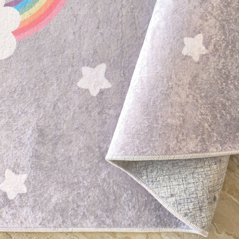 Tapis gris à la texture douce, décoré d'étoiles blanches et d'un arc-en-ciel coloré, un coin est plié