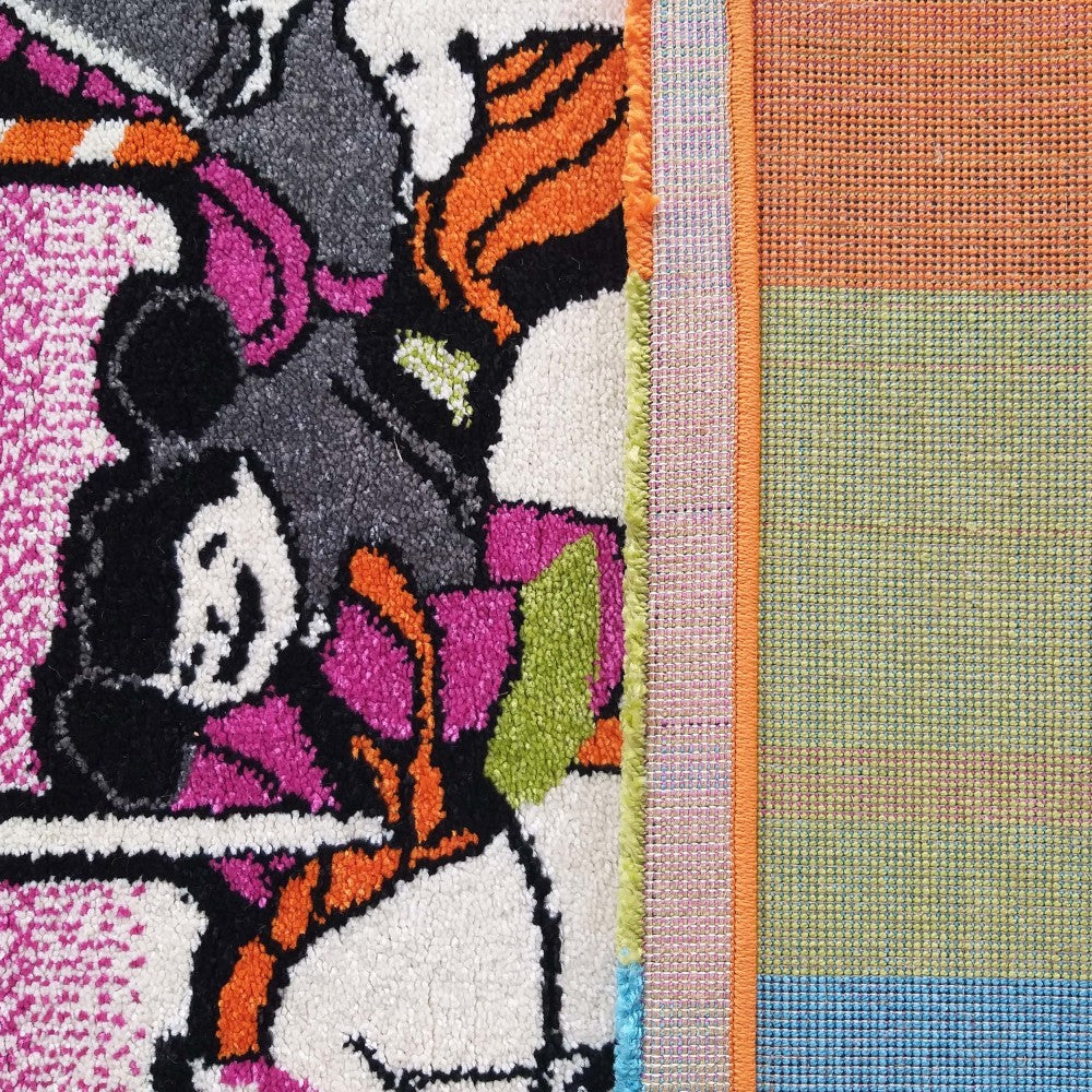 Tapis présentant son côté motif coloré à texture de poils et son envers tissé à rayures orange, vert et bleu